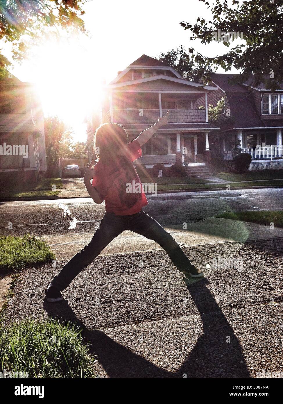Boy playing in yard with flair from sun. - Smartphone Captured Stock Image
