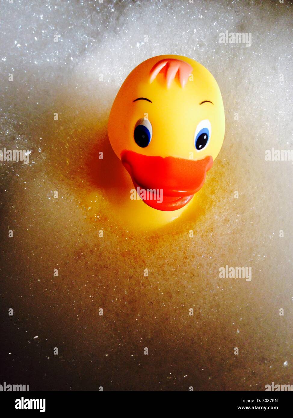 Image of a yellow plastic duck floating on foamy bubbles - Smartphone Captured Stock Image