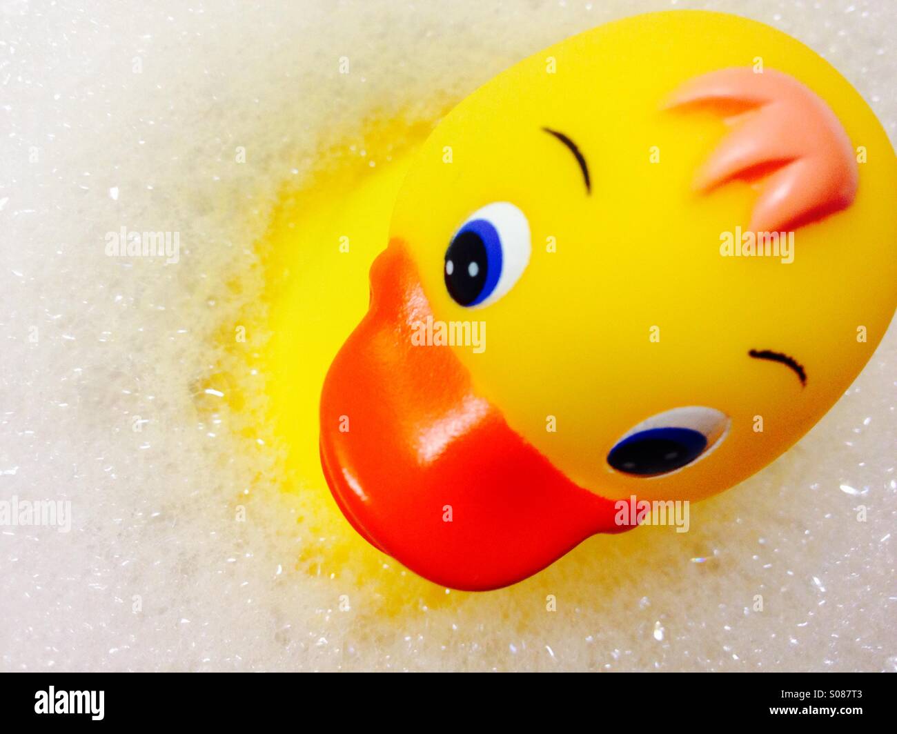 Image of a yellow plastic duck floating on foamy bubbles - Smartphone Captured Stock Image