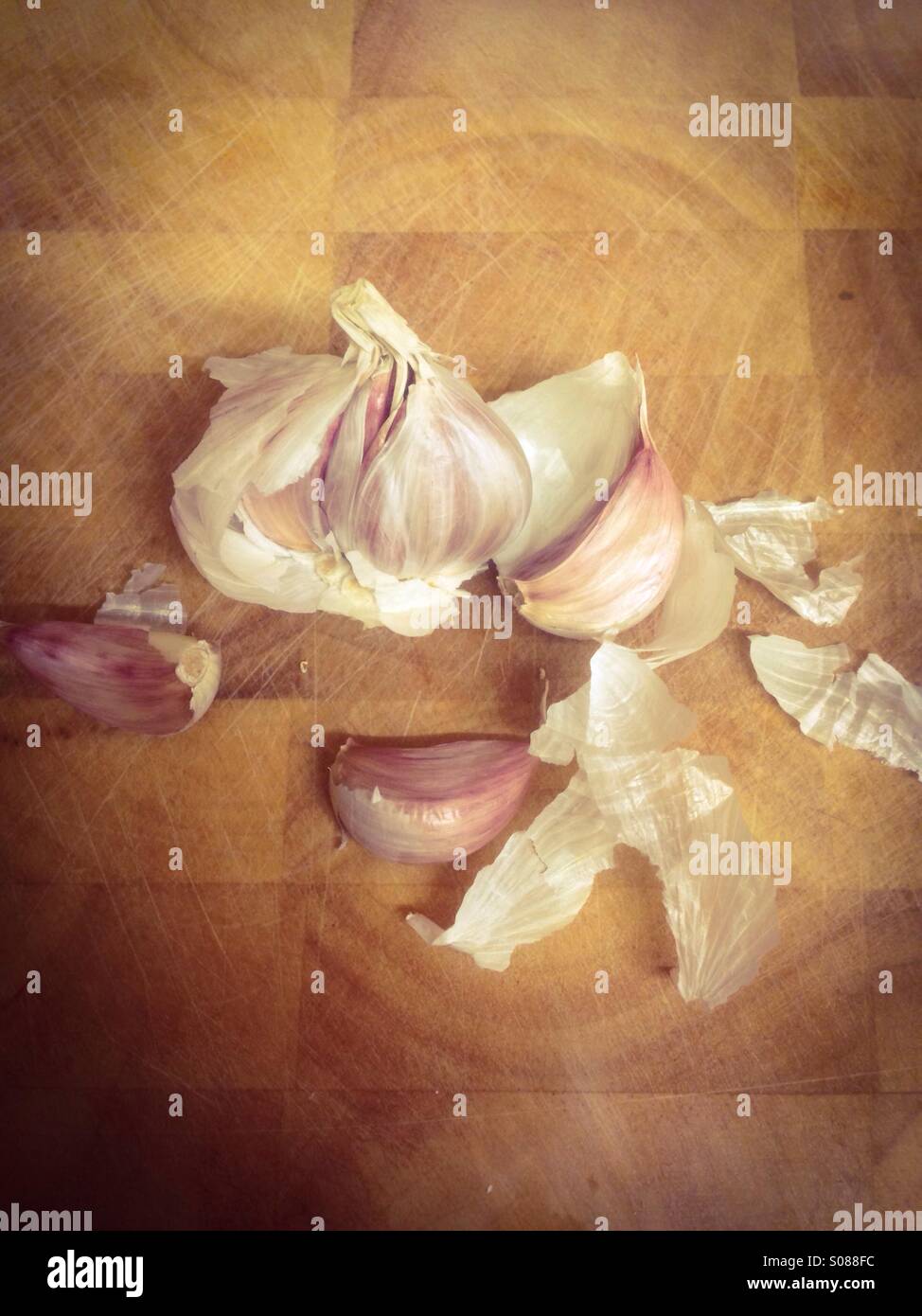 Smashed garlic bulb on a wooden chopping board - Smartphone Captured Stock Image