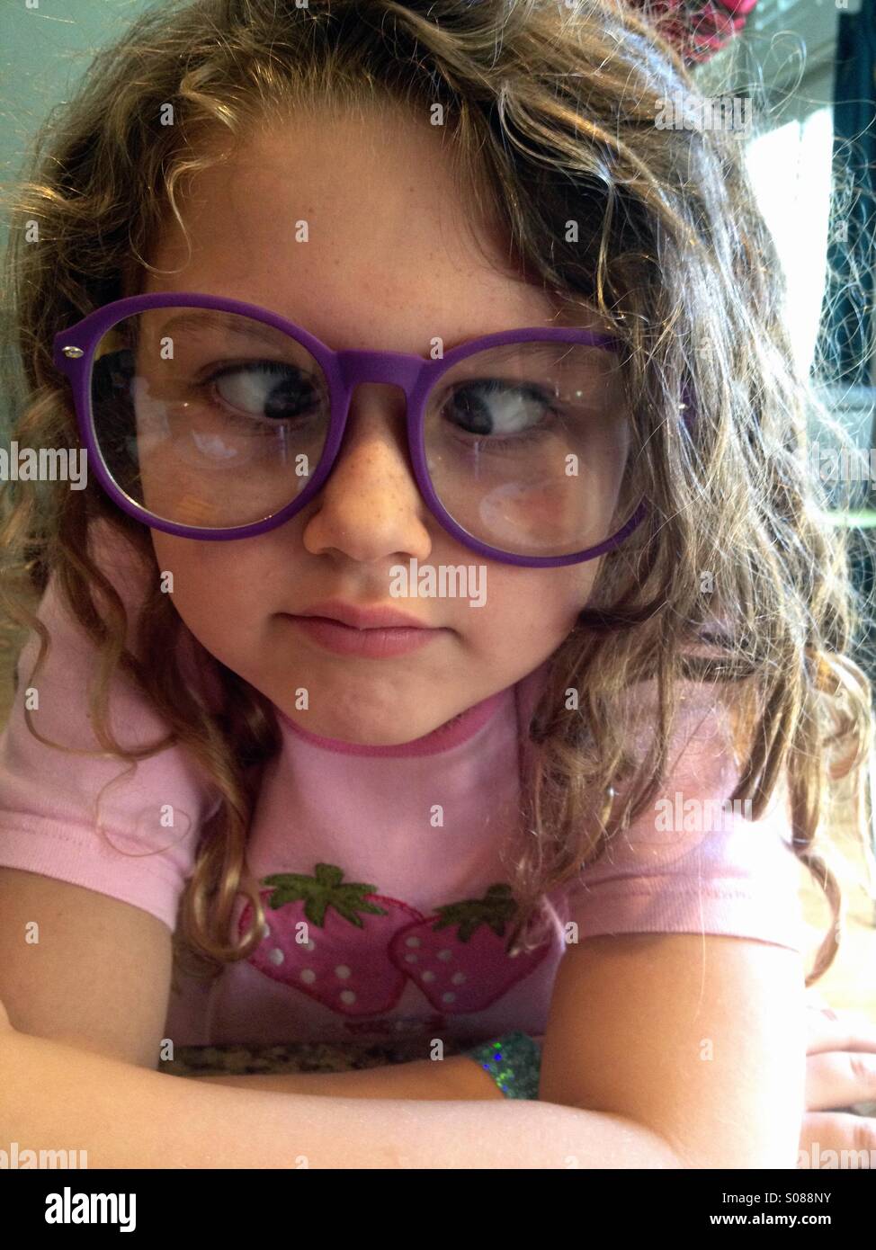 Young girl wearing big glasses and playing cross eyed. Stock Photo
