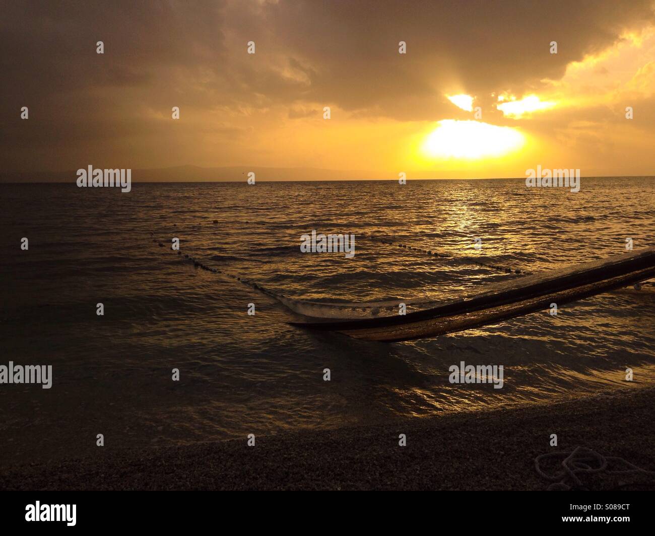 Pulling fishing net near shore with sunset background Stock Photo
