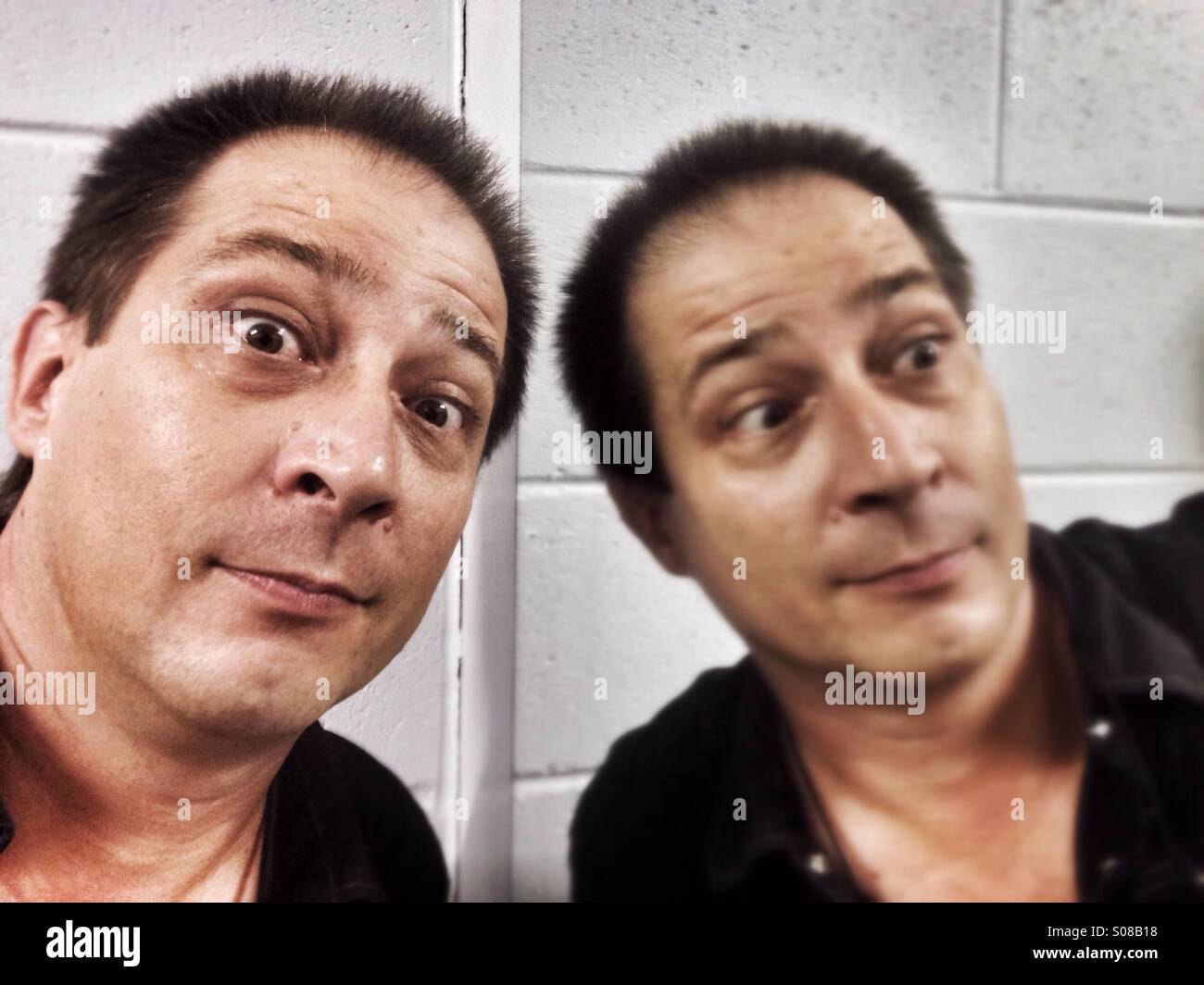 Man looking at the camera, with his reflection in a mirror. - Smartphone Captured Stock Image