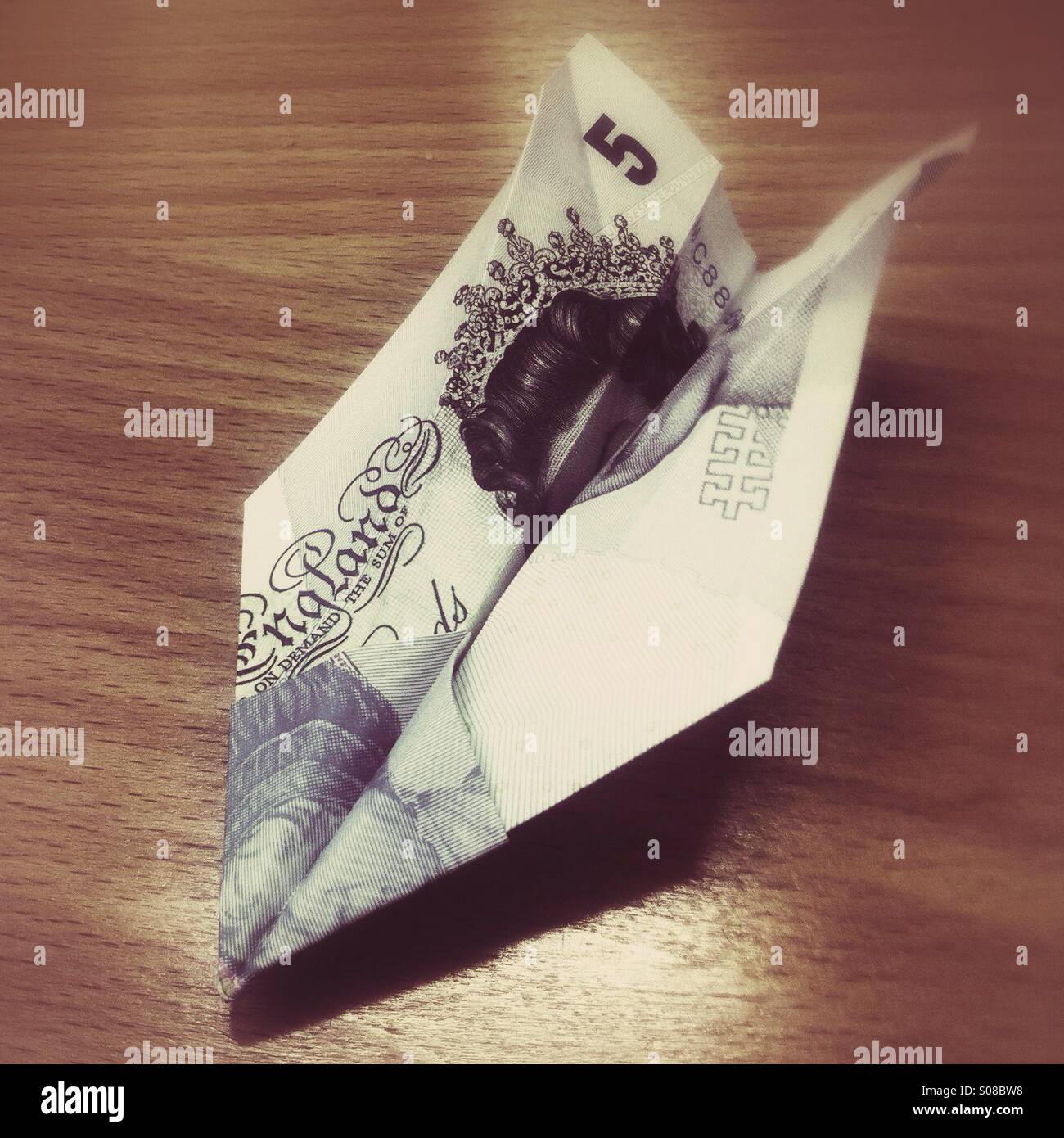 Five pound note folded into a paper plane - Smartphone Captured Stock Image
