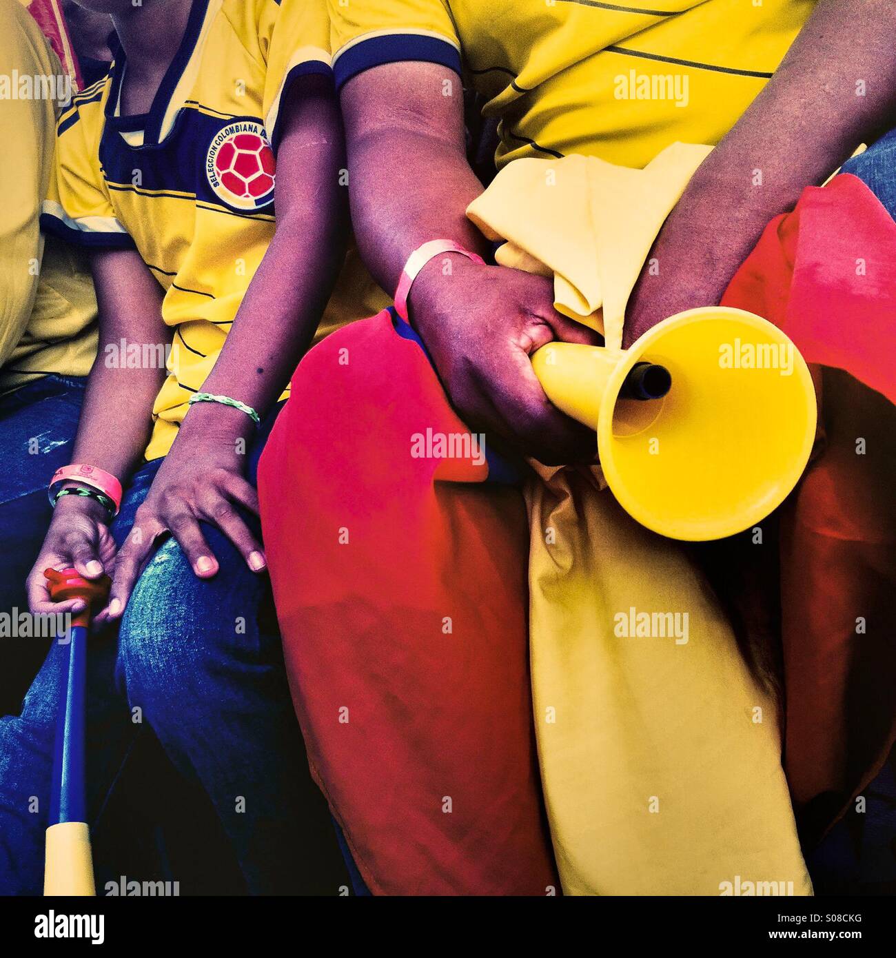 Colombia football fans hold trumpets while watching the football match between Colombia and Japan at the FIFA World Cup 2014, in a park in Cali, Colombia, 24 June 2014. Stock Photo
