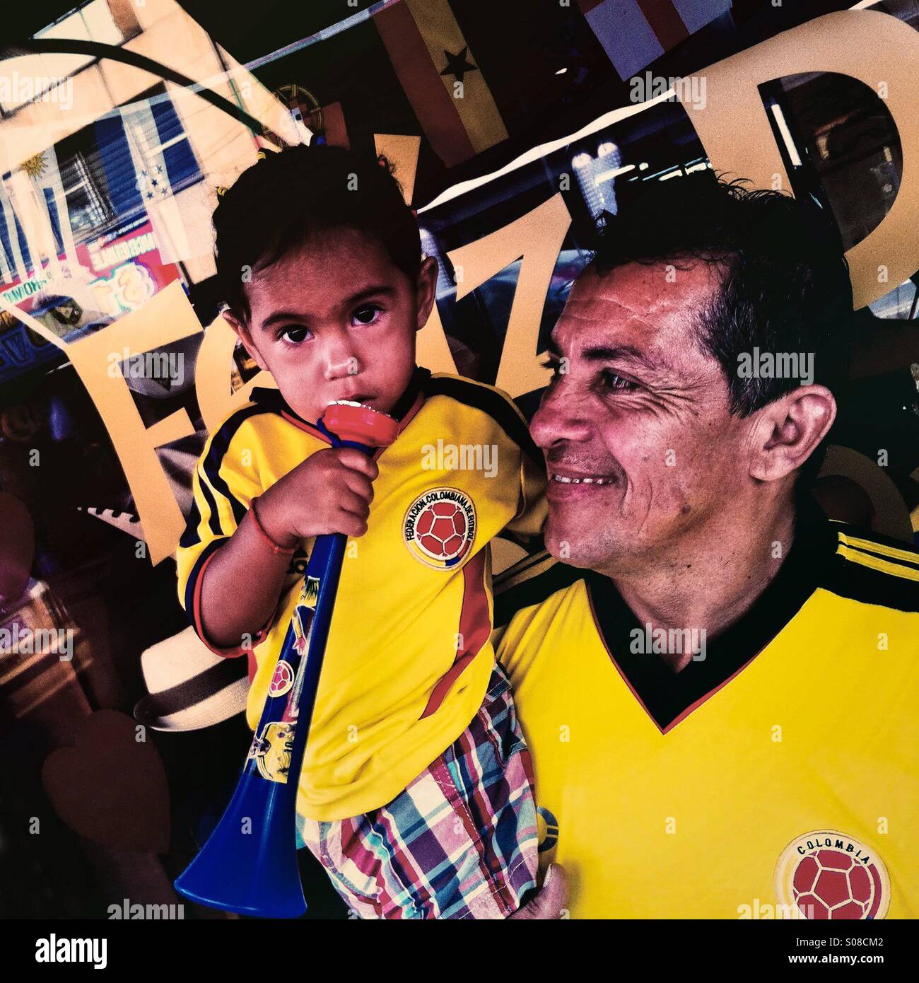 A Colombian father holds his baby girl, both wearing the national football team t-shirt, on the street in Cali, Colombia, 28 June 2014. Stock Photo