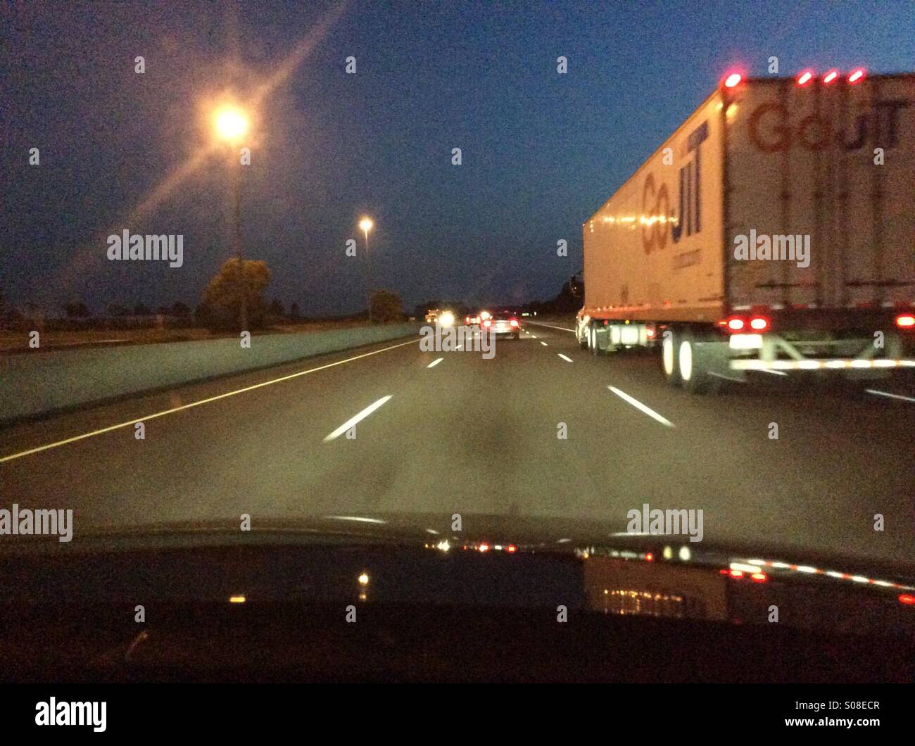 Truck at night on a multi lane highway. View from the passenger side of a car in the adjacent lane. - Smartphone Captured Stock Image