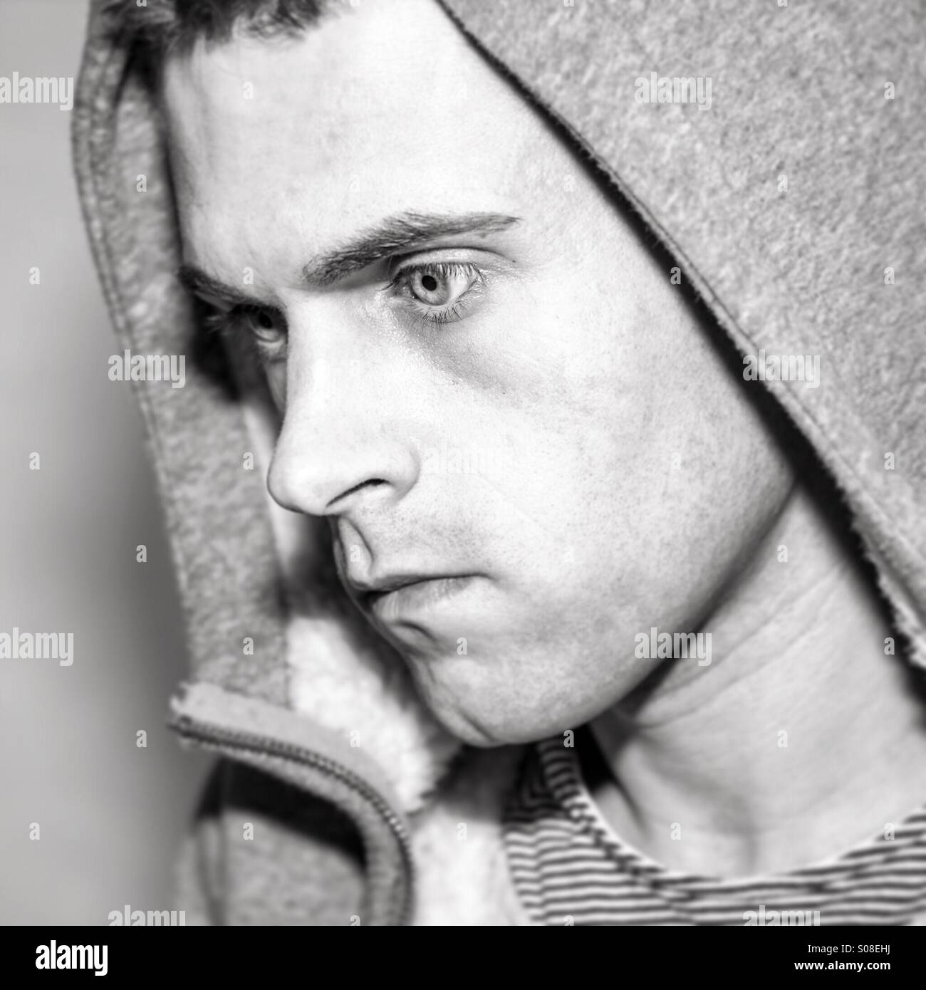 Young male staring away from camera wearing hood - Smartphone Captured Stock Image
