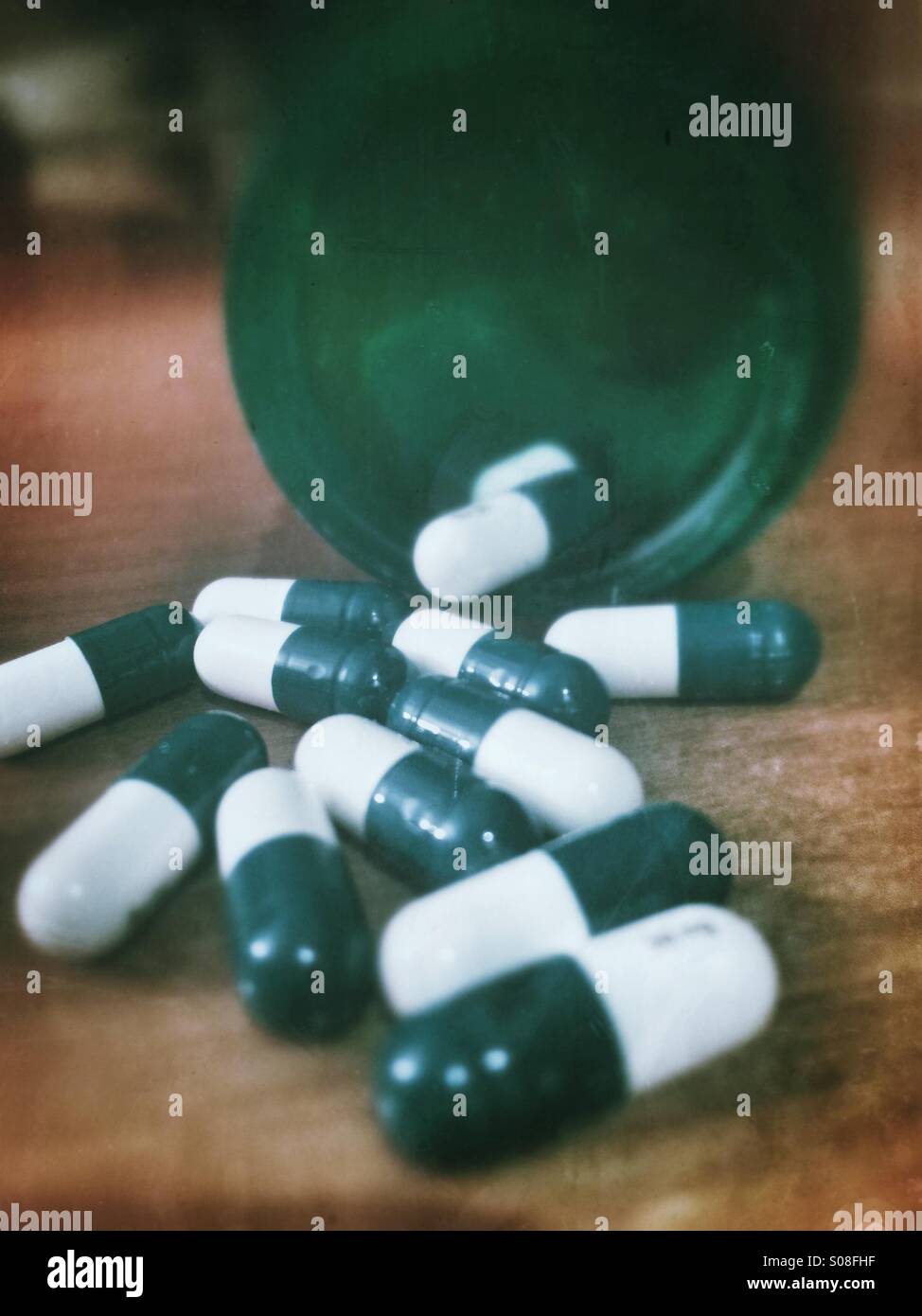 Green and white pills spilled out on a table - Smartphone Captured Stock Image