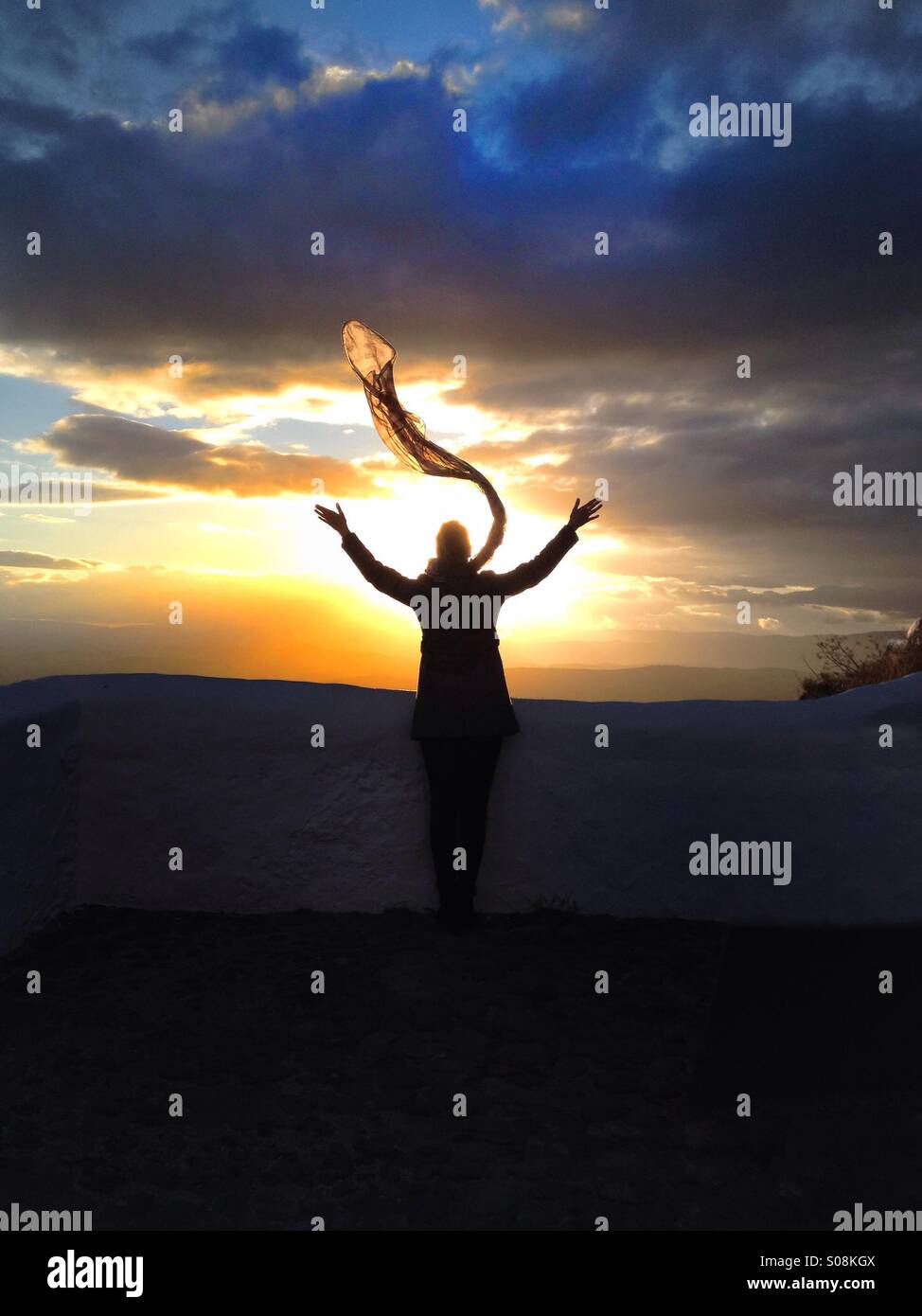 Woman with scarf watching sunset Stock Photo