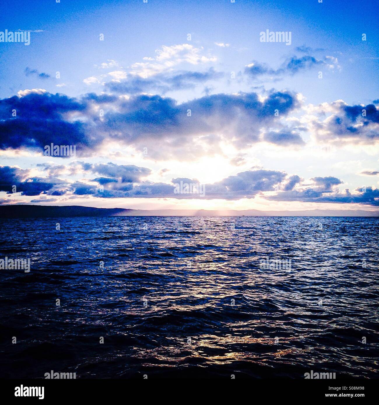 Beautiful sunset at sea with many clouds above Stock Photo
