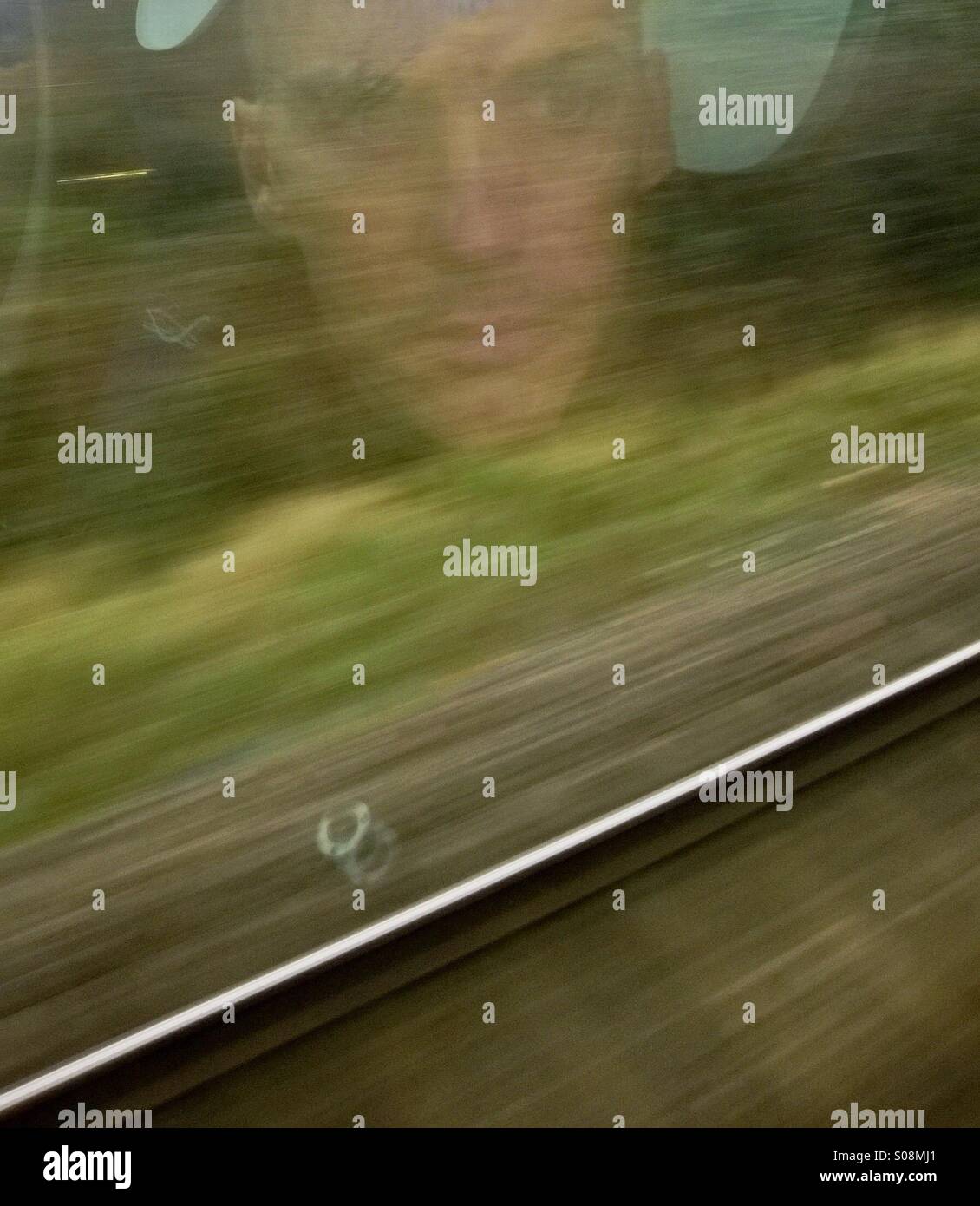 Portrait of man reflected in train window while travelling. - Smartphone Captured Stock Image