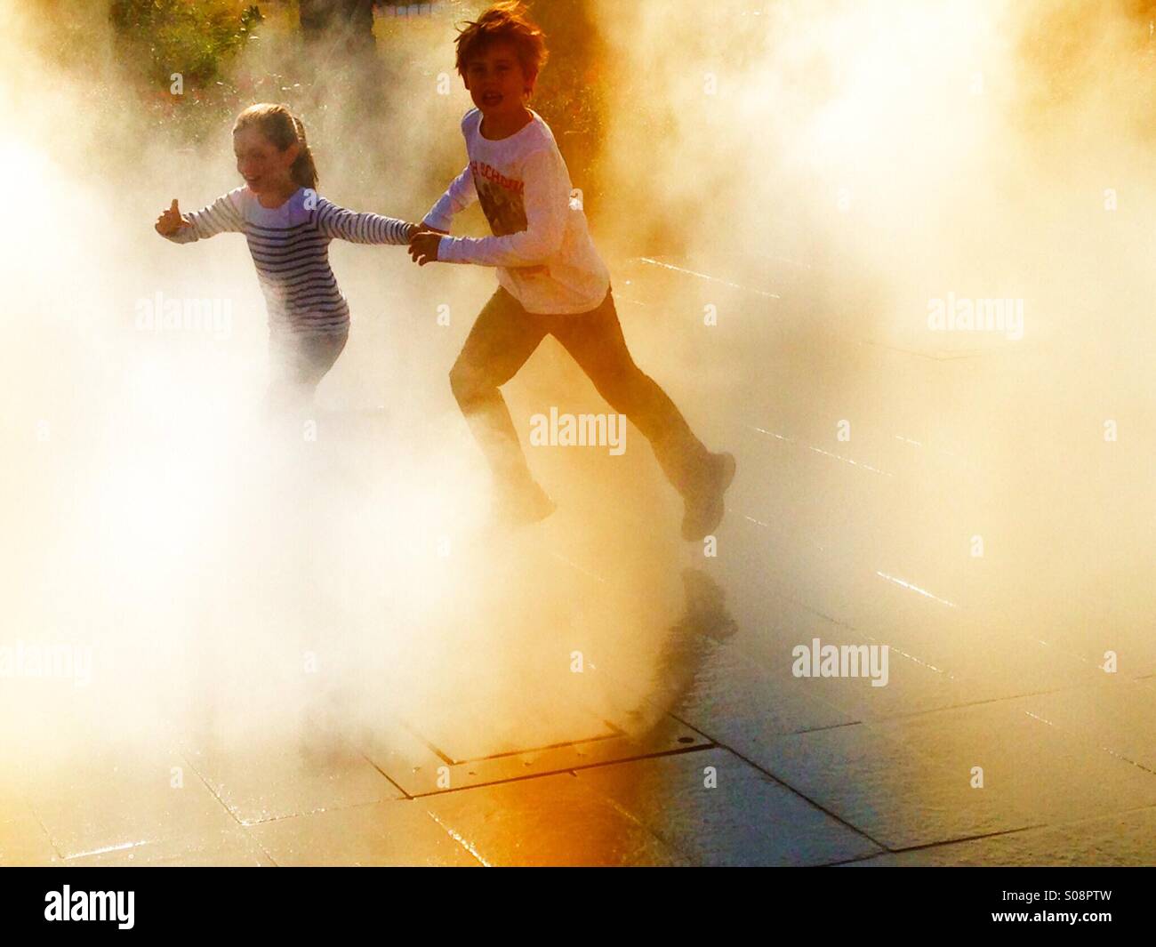 Boy and girl running through the mist - Smartphone Captured Stock Image