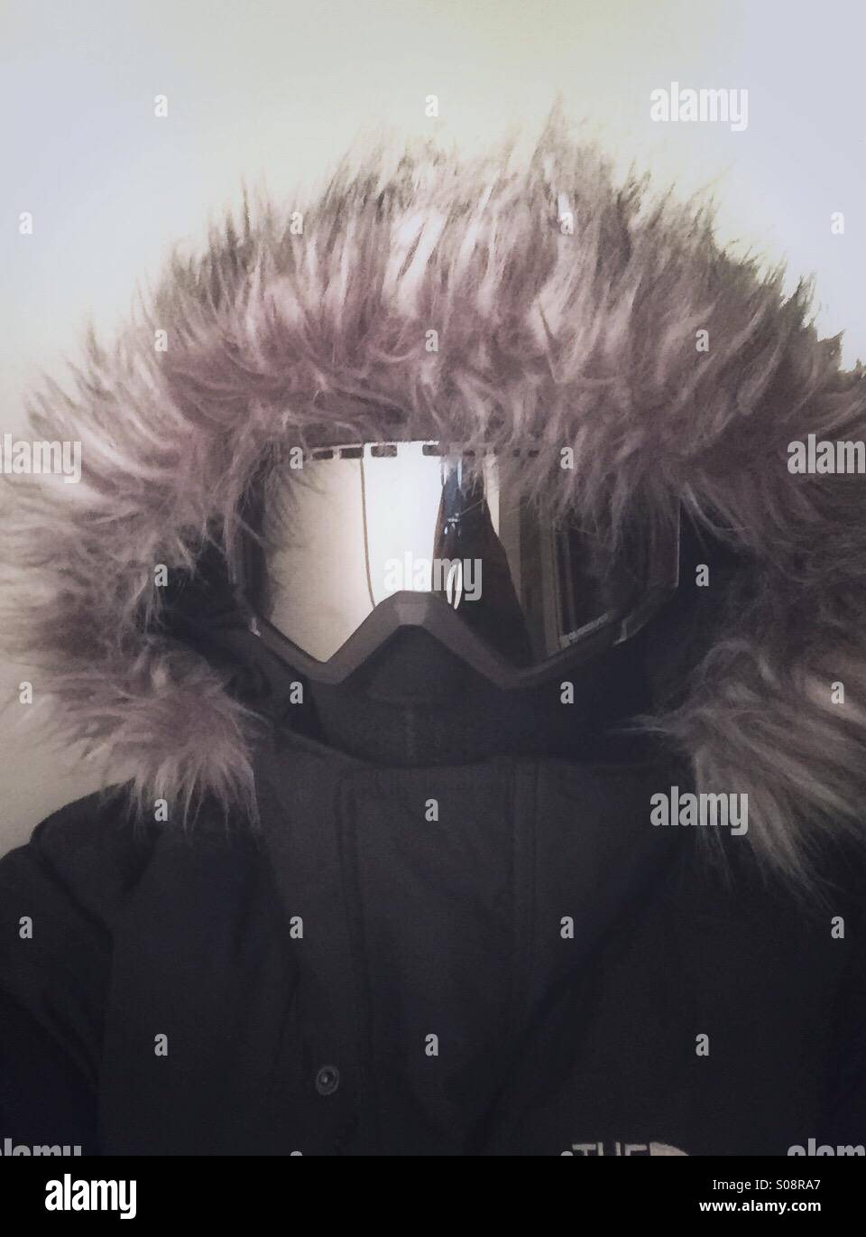 A guy wearing winter coat with a fur hood, ski mask and ski goggles - Smartphone Captured Stock Image