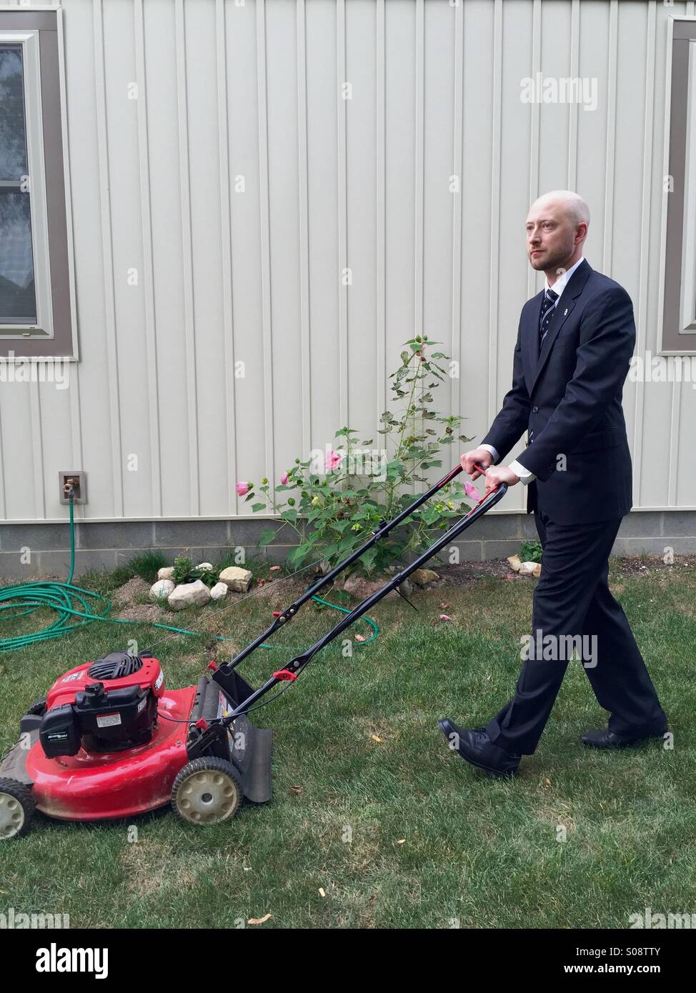 Businessman mowing the lawn in a suit Stock Photo Alamy