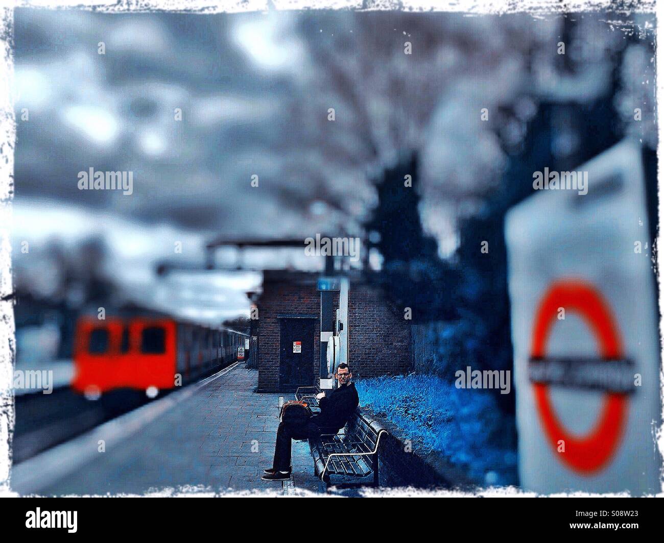 Man waiting for train at Ealing Common tube station, West London, UK Stock Photo