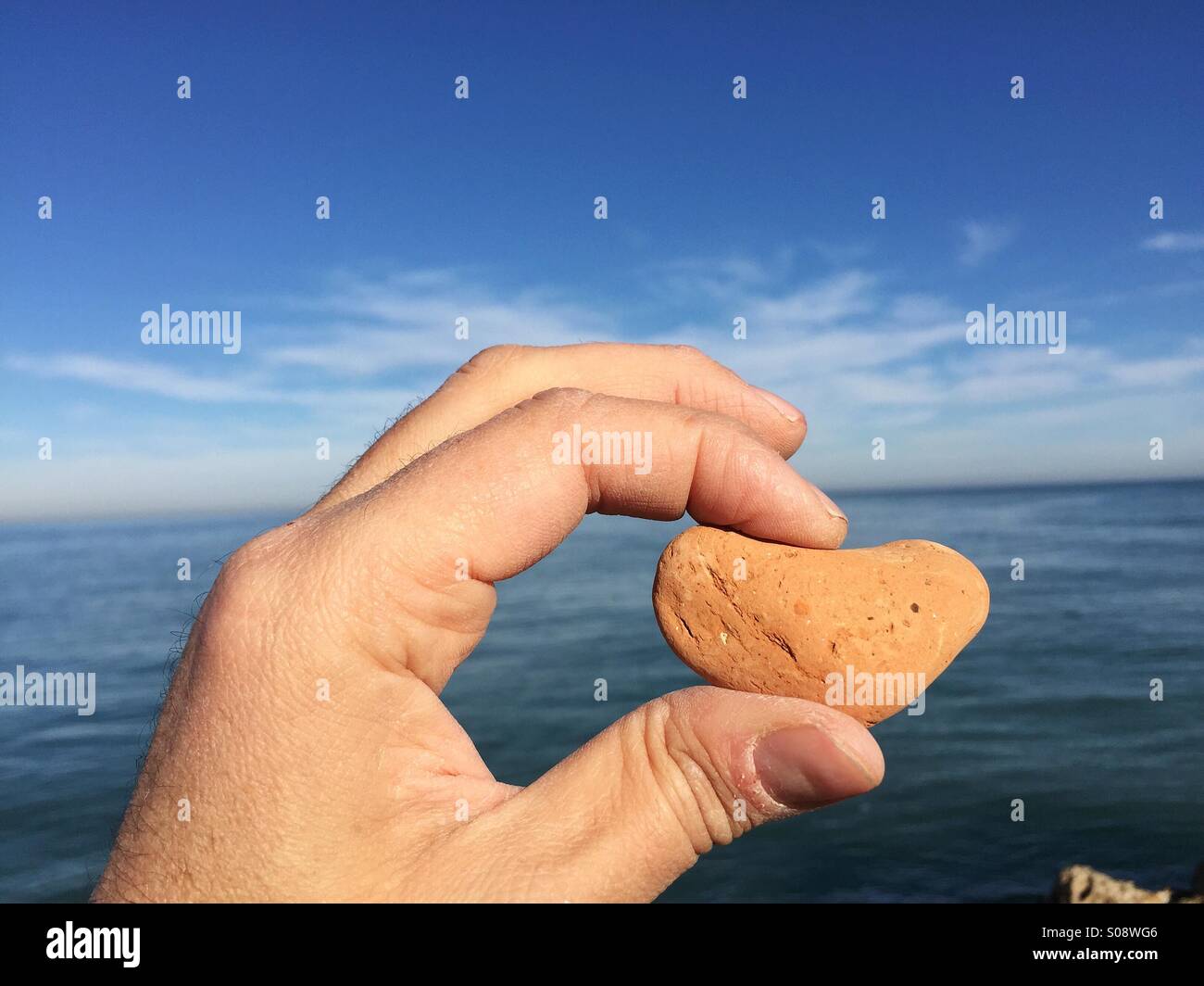 Love message conceptual image with a stone heart between fingers Stock Photo