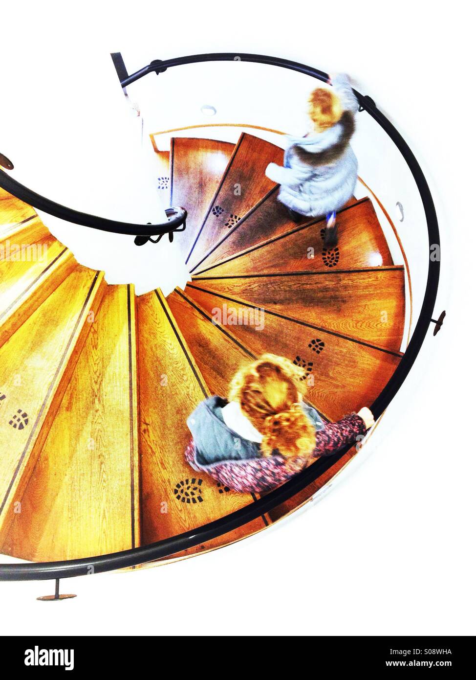 Two children walking down spiral staircase viewed from above - Smartphone Captured Stock Image