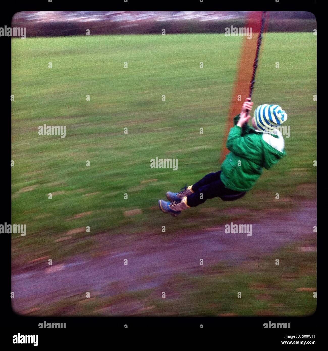 Five year old boy playing on a zip wire, photographed with movement blur Stock Photo