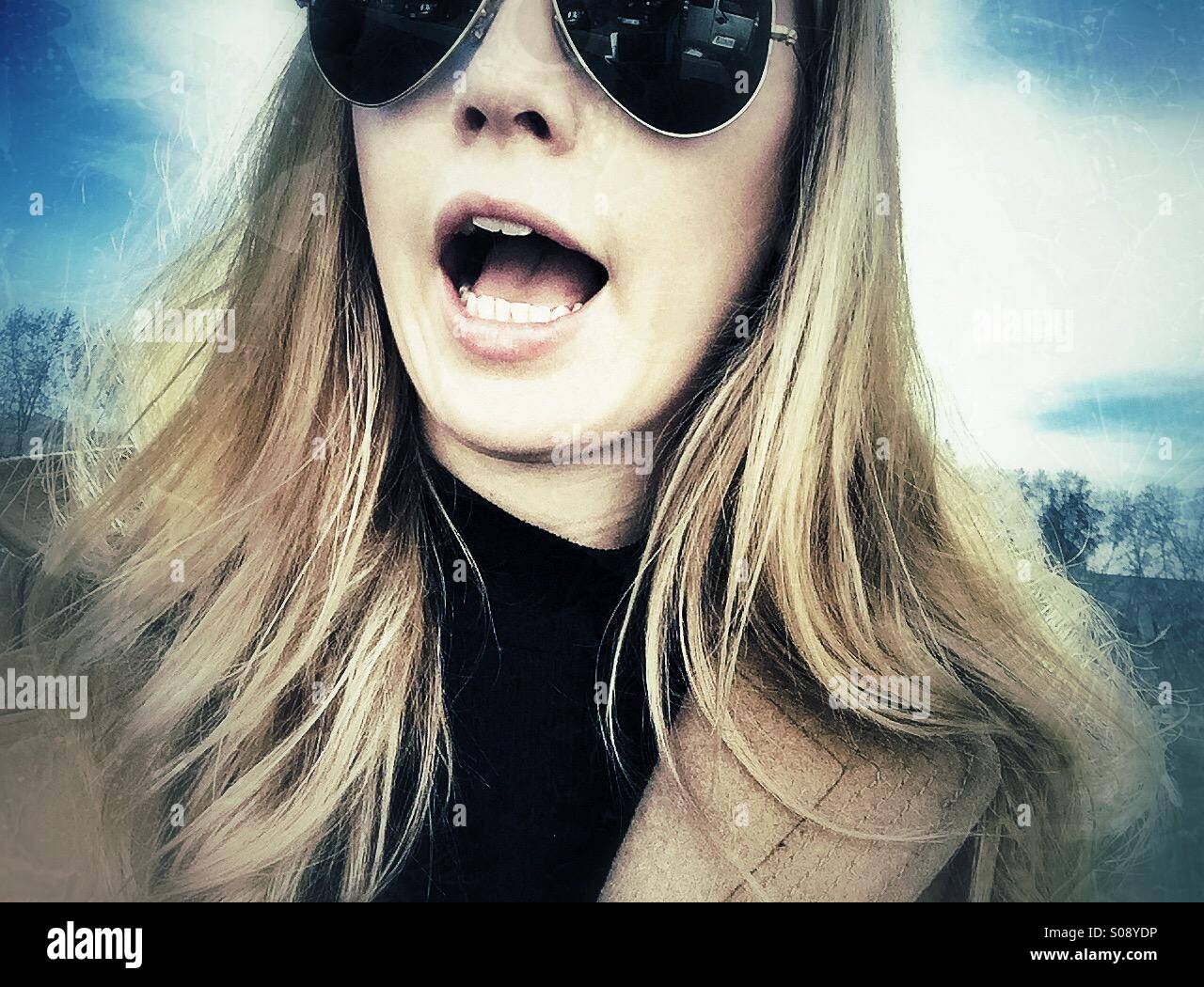 Young woman with blond hair and sunglasses shouting Stock Photo