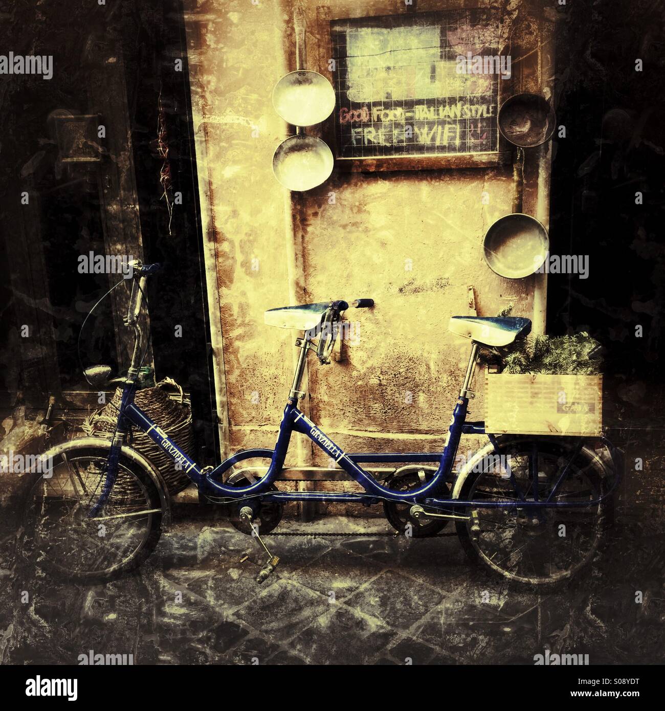 An old fashioned tandem bike leaning against a wall in Rome Stock Photo