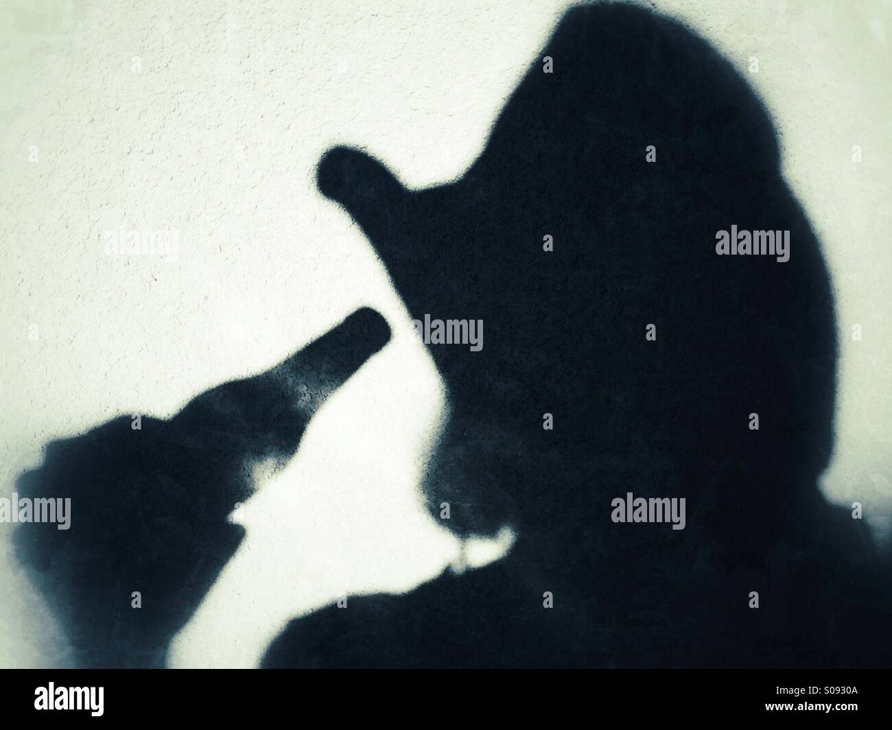 Shadow of a female wearing a cowboy hat drinking from a beer bottle Stock Photo