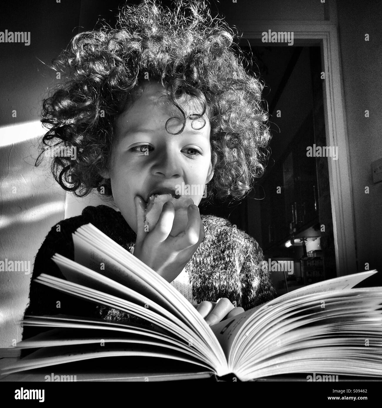 Girl eating an apple while reading a book. Stock Photo