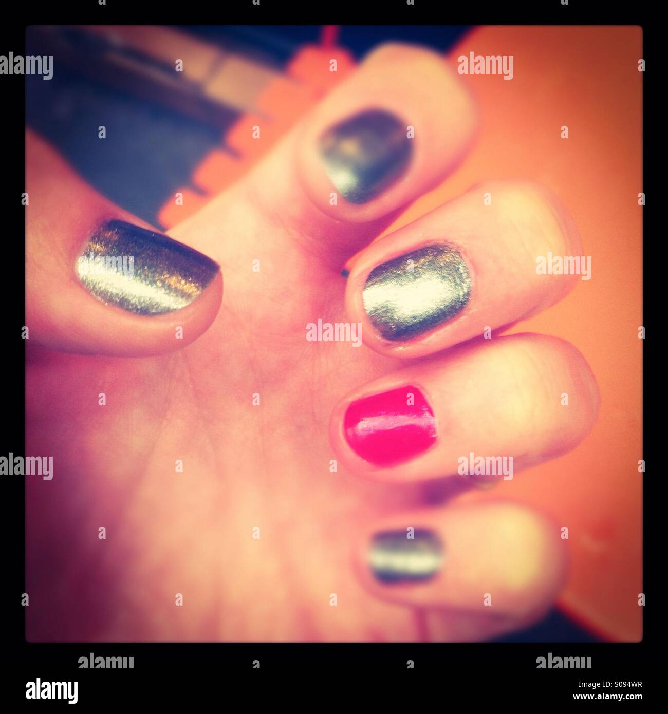 Hand with nails painted silver and red on the ring finger Stock
