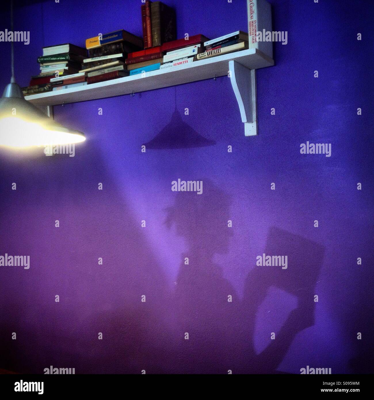 A shadow of a woman using an Ipad cast on a purple wall in Fika coffee shop in Colonia Roma, Mexico City, Mexico - Smartphone Captured Stock Image