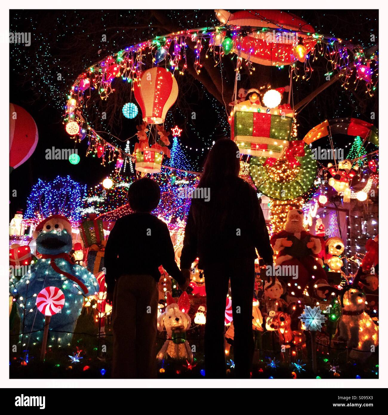 Eleven year old girl and her six year old brother hold hands while looking at Christmas lights. - Smartphone Captured Stock Image