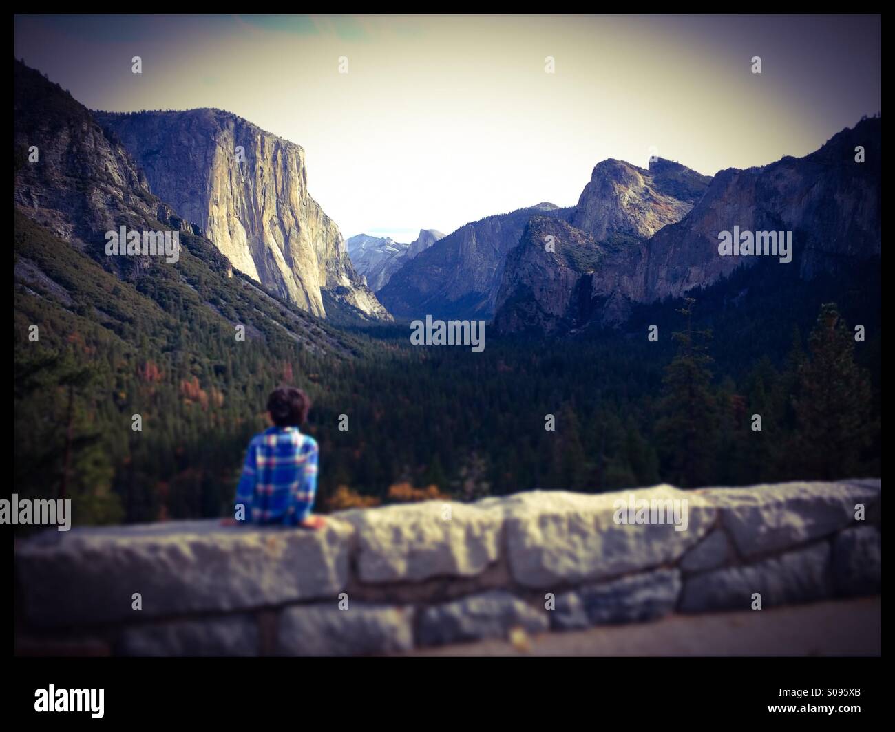 A six year old boy enjoys the view of Yosemite Valley during fall from the famous Tunnel View Vista on Wawona Road. Yosemite National Park, Mariposa County, California, USA - Smartphone Captured Stock Image