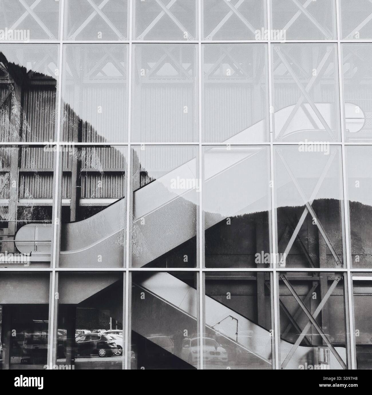Escalators in a modern glass building with a mountain reflected in the glass - Smartphone Captured Stock Image