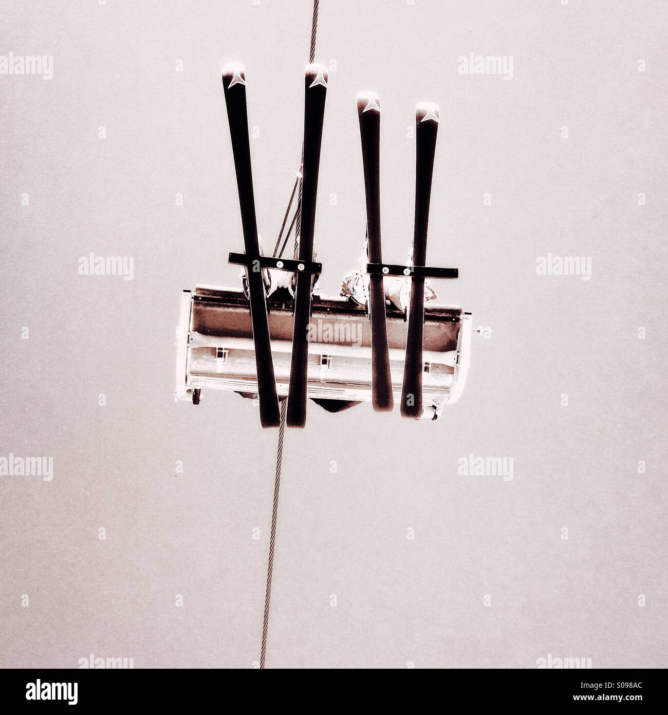 Skiers heading up the mountain on a chairlift viewed from below - Smartphone Captured Stock Image