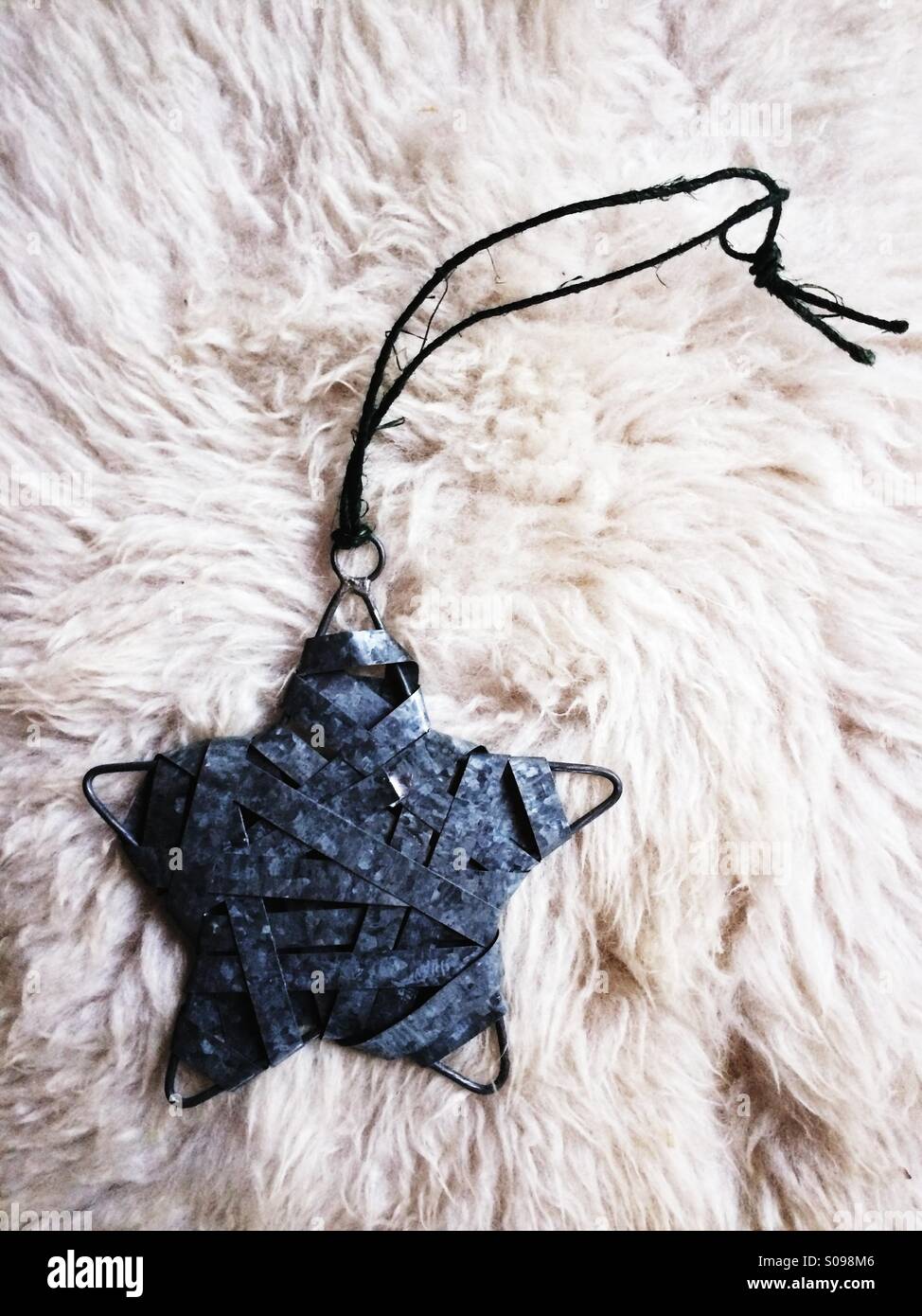 Dark metal star ornament on a white sheepskin. - Smartphone Captured Stock Image