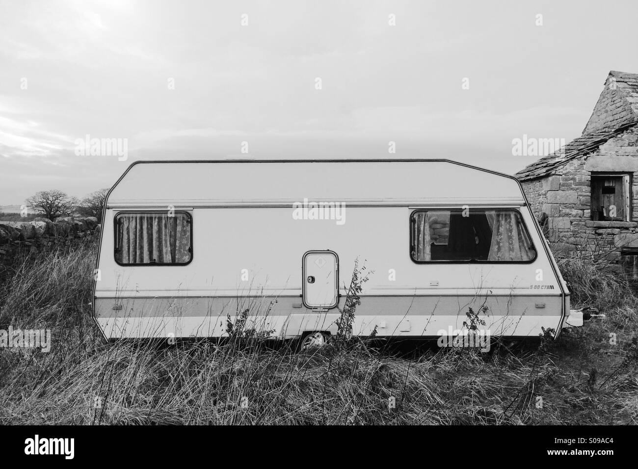 An abandoned caravan or camper trailer in black and white in rural England. Stock Photo