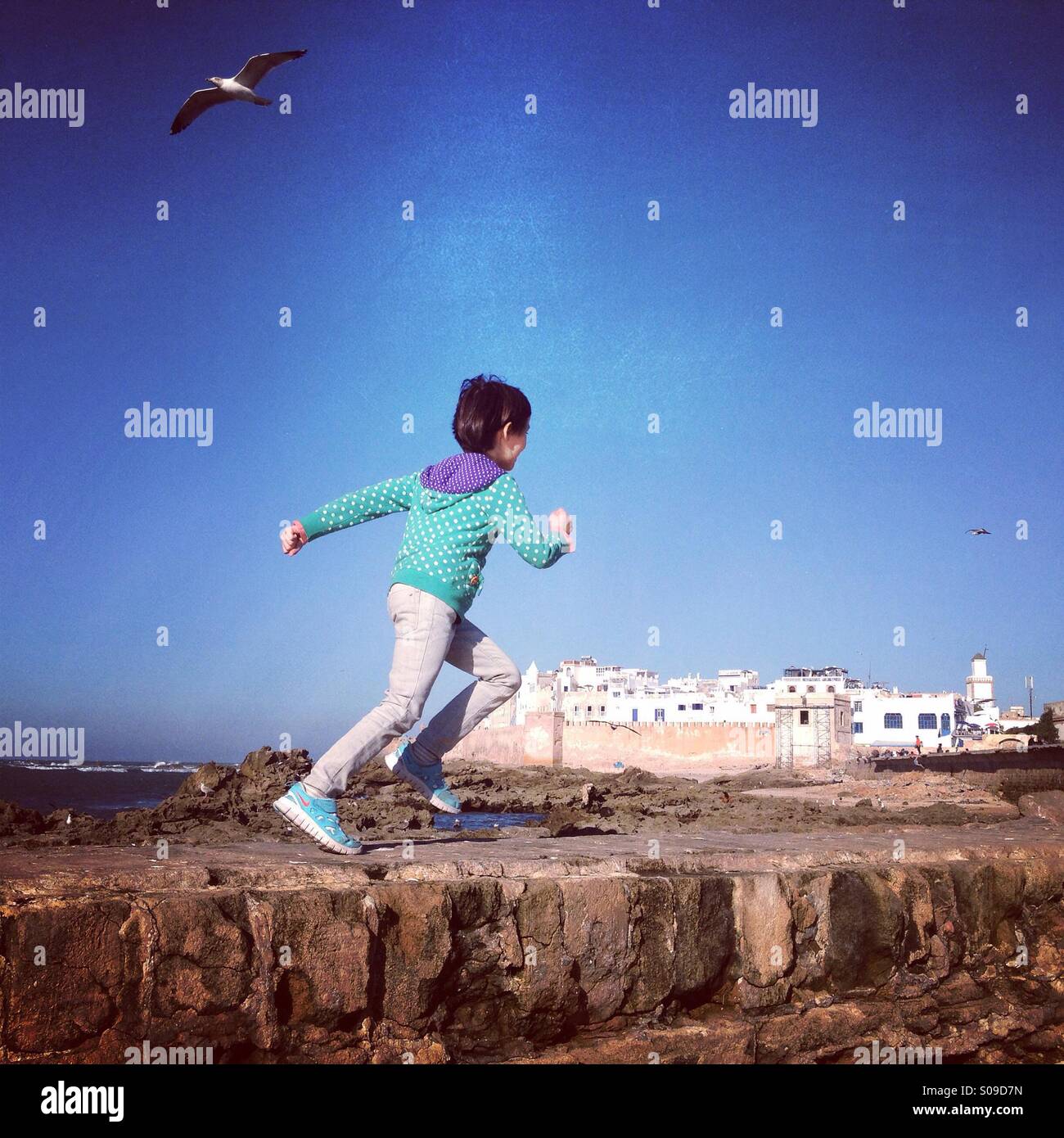 Child running on harbour wall in Essaouira port, Morocco. Stock Photo