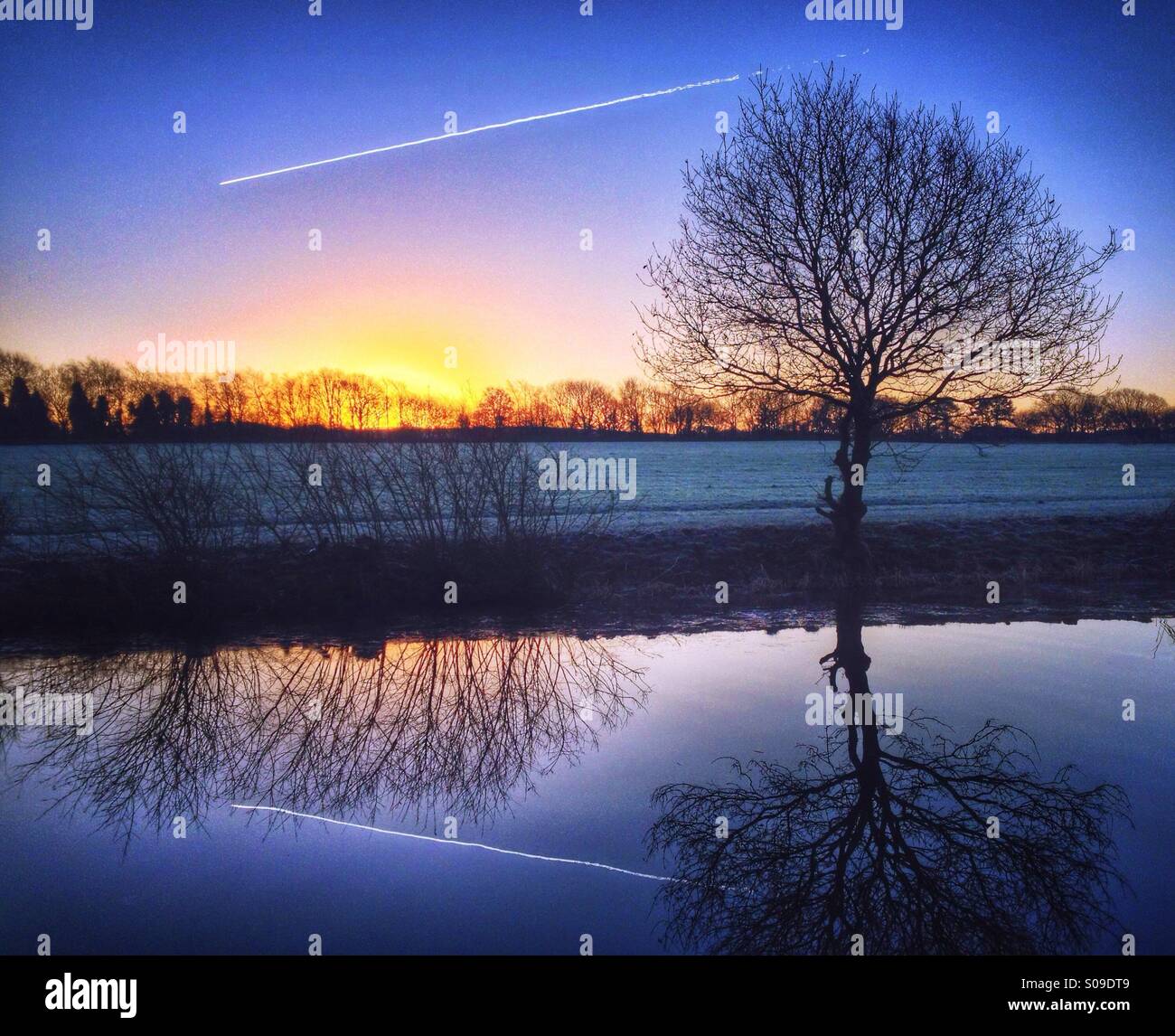 Vapour trail and reflection at sunrise - Smartphone Captured Stock Image
