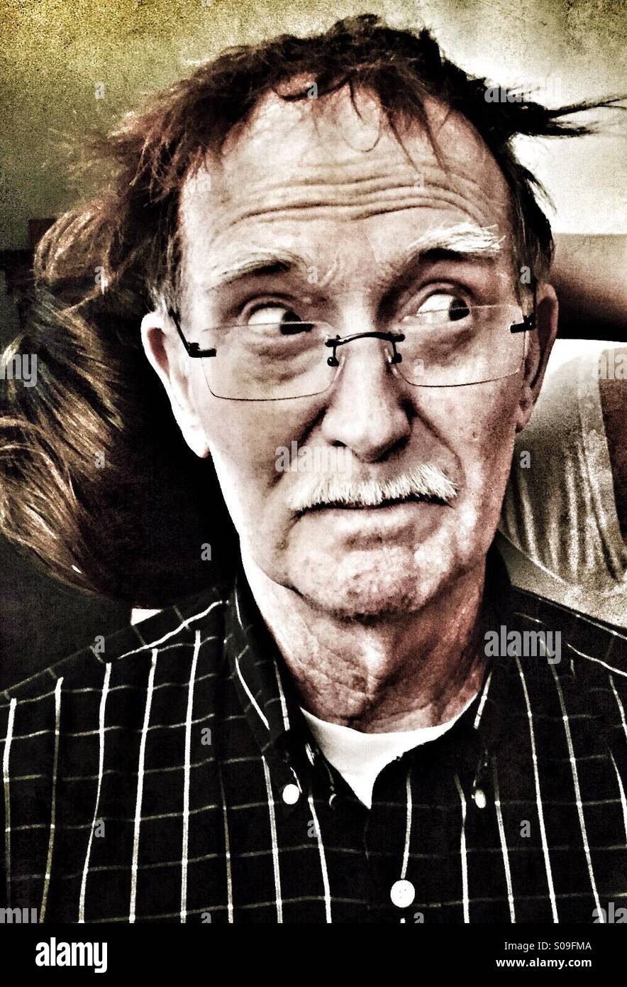 An old man is surprised when a female relative lays some of her long hair over his bald head. - Smartphone Captured Stock Image