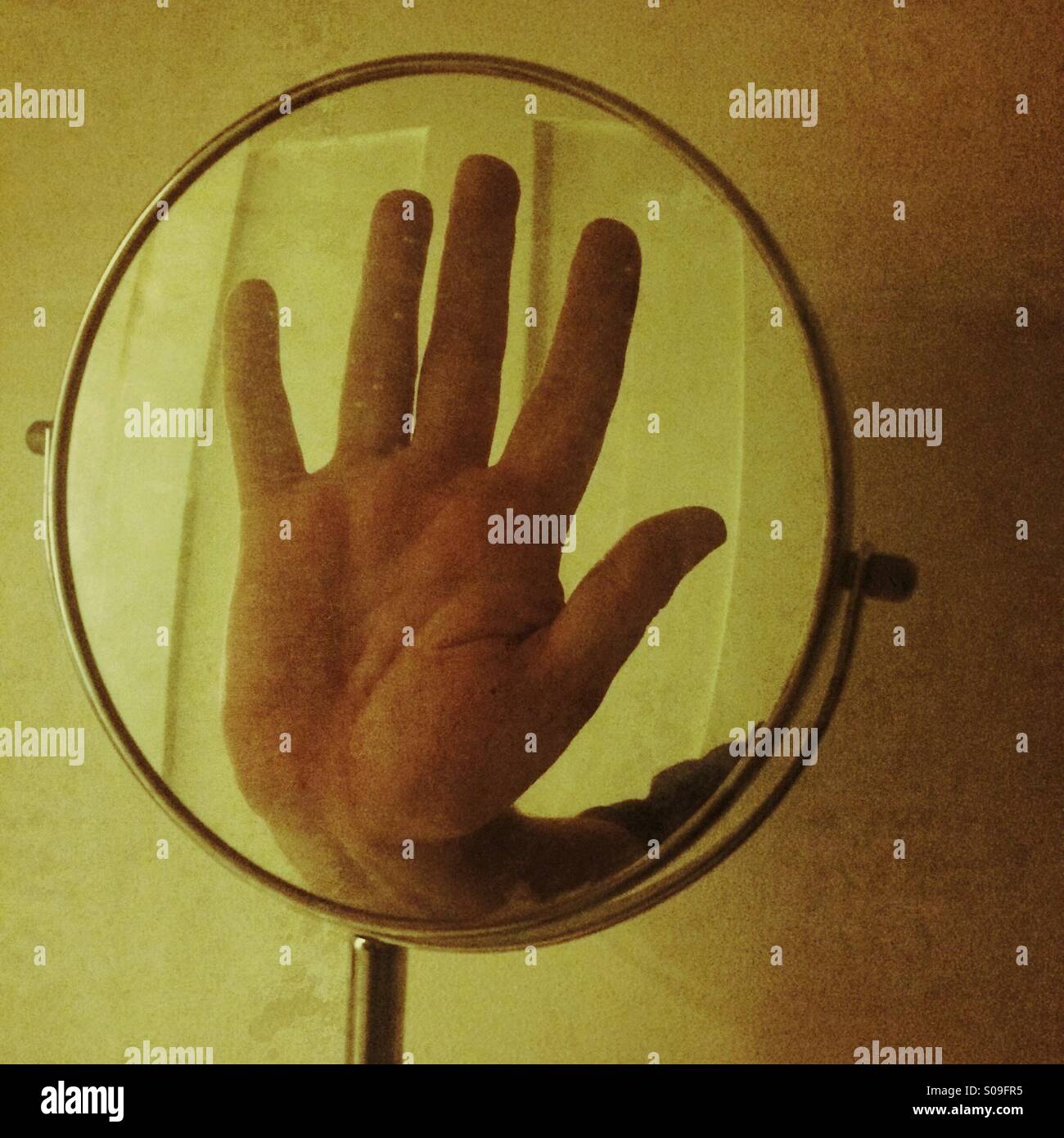 A reflection of a hand in a small mirror - Smartphone Captured Stock Image