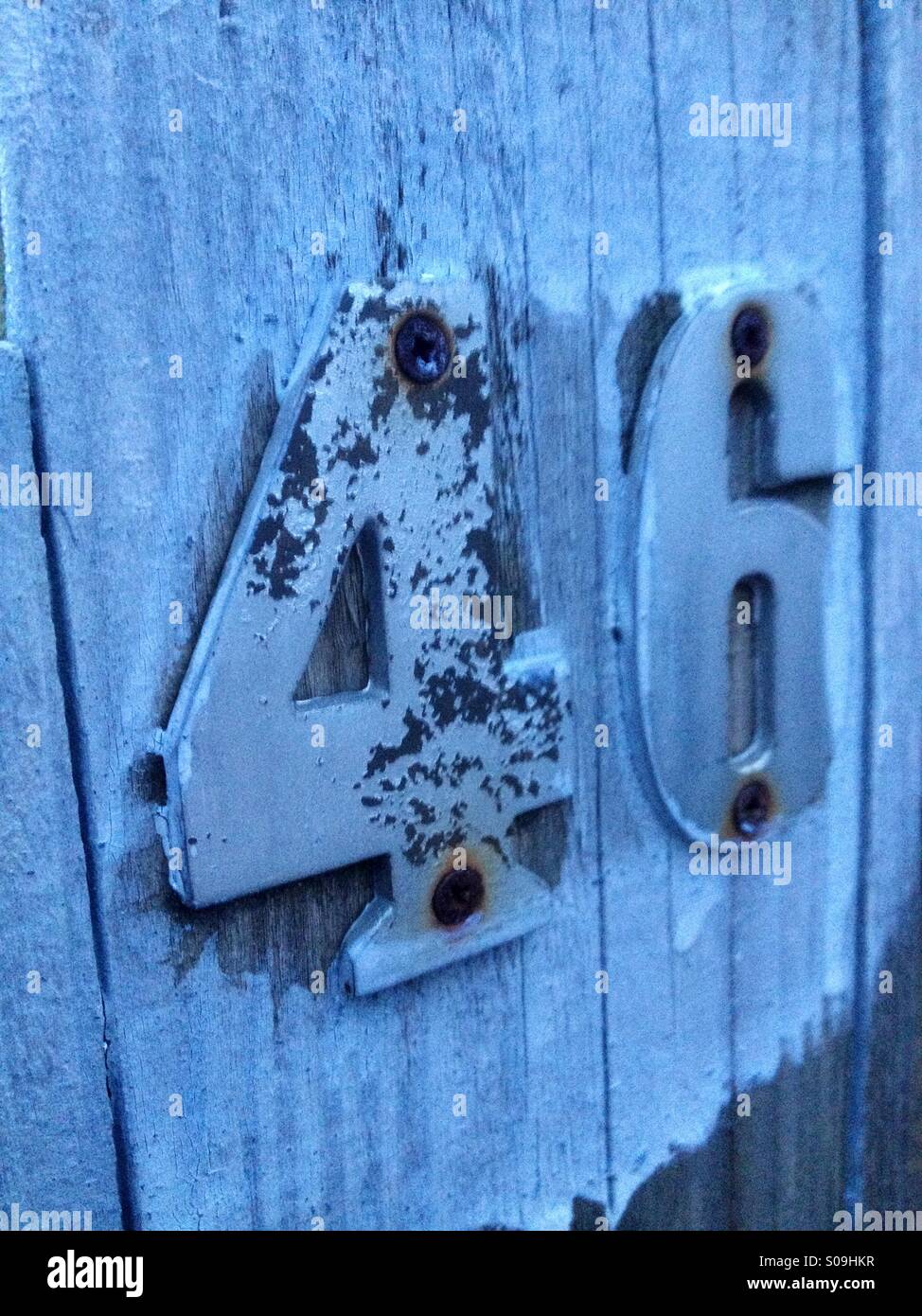 House number 46 rusted and painted on wood Stock Photo