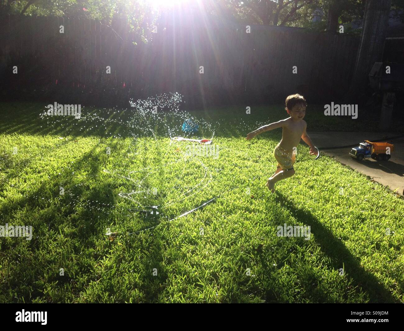 Child running through sprinklers hires stock photography and images