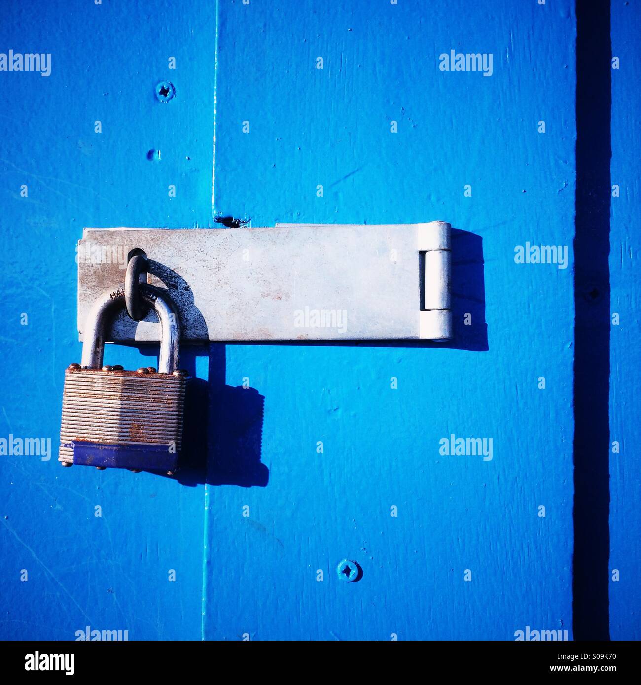 A locked padlock on a blue wooden door. Stock Photo