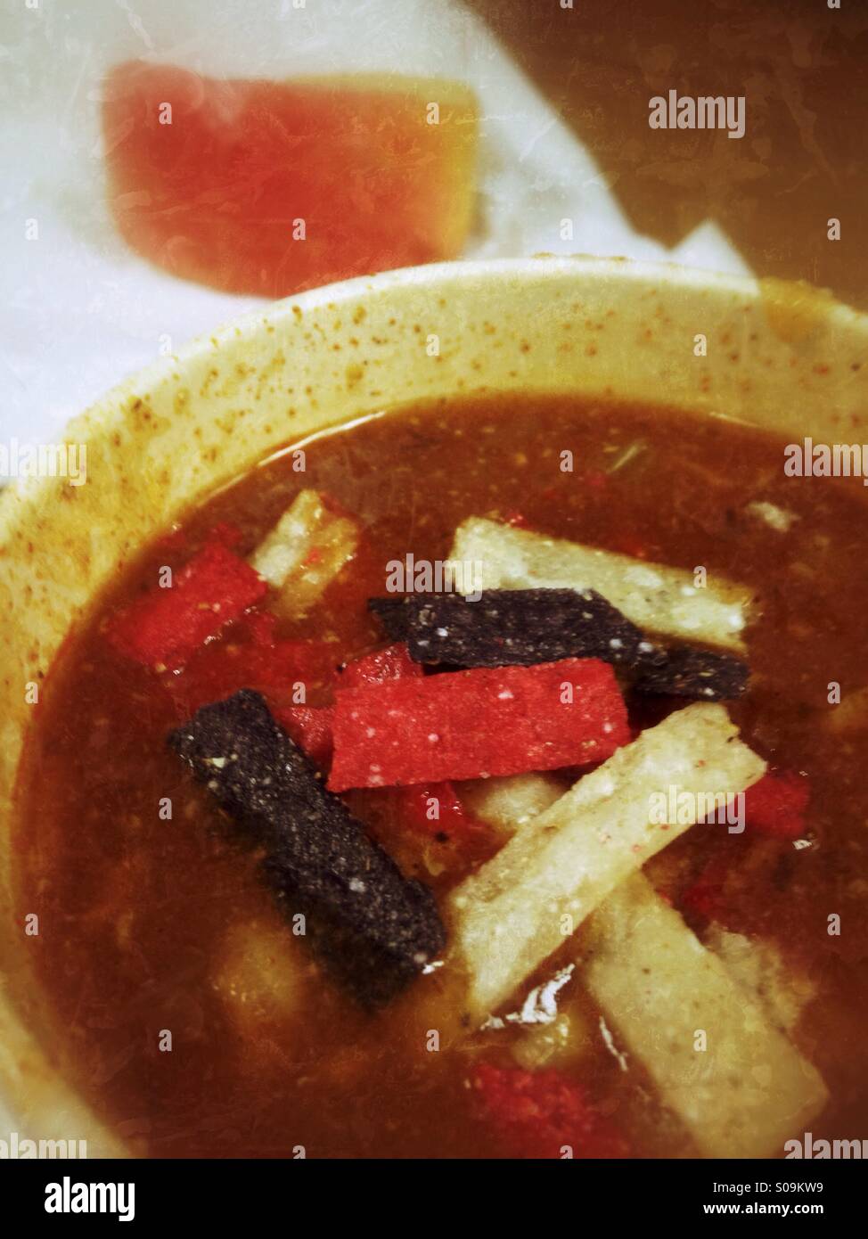 Chicken chili topped with tricolor  tortillas with an apple slice in the background. - Smartphone Captured Stock Image