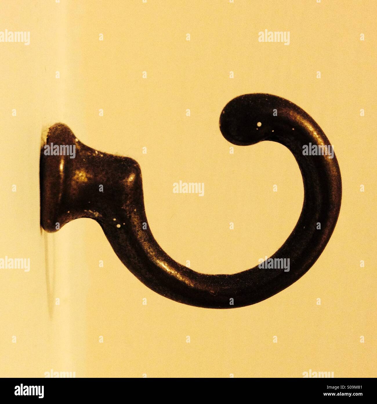 Side on view of a bronze coloured hook on a wall Stock Photo