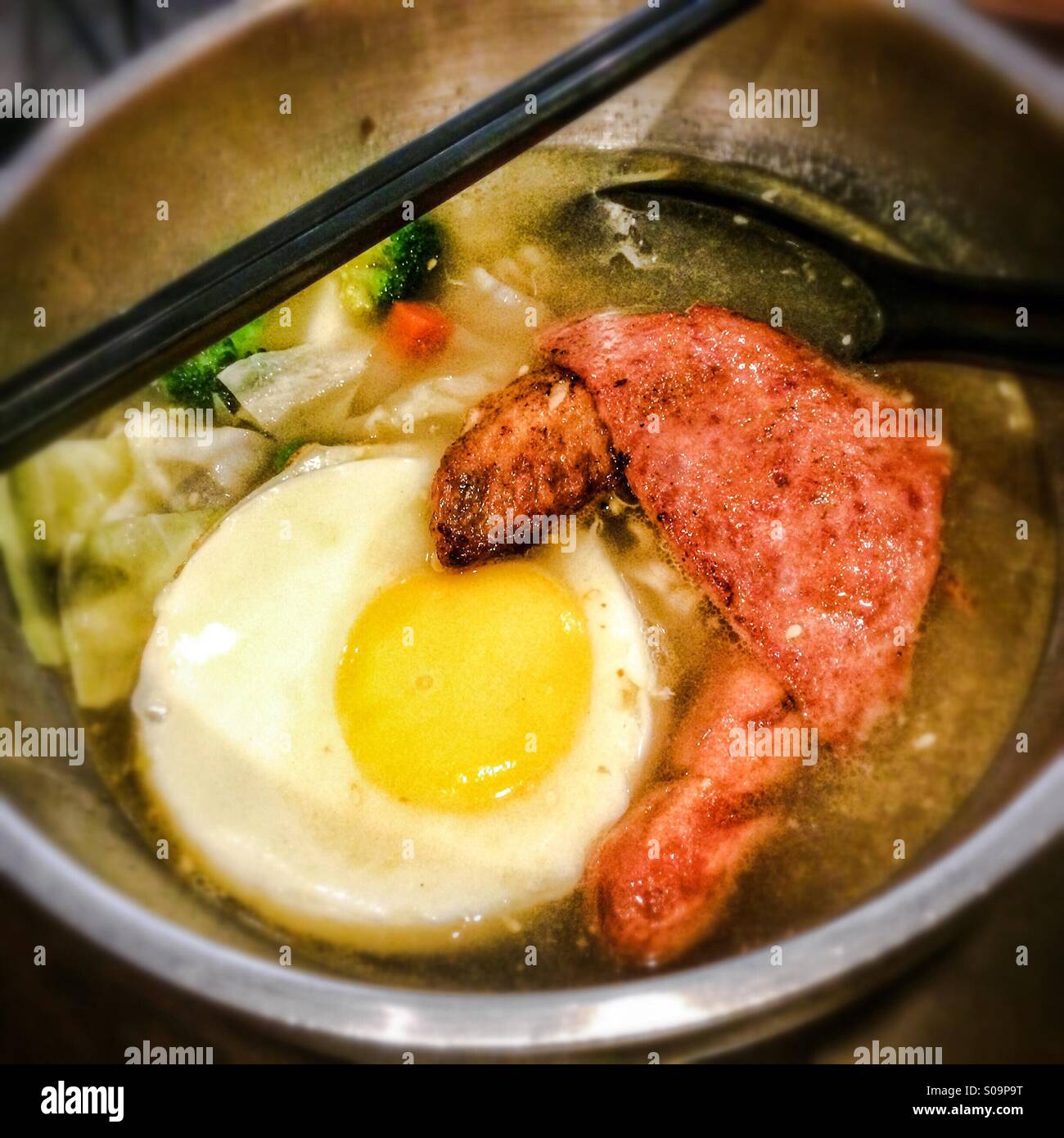 Bowl of noodle soup with egg chicken ham sausage and vegetables - Smartphone Captured Stock Image