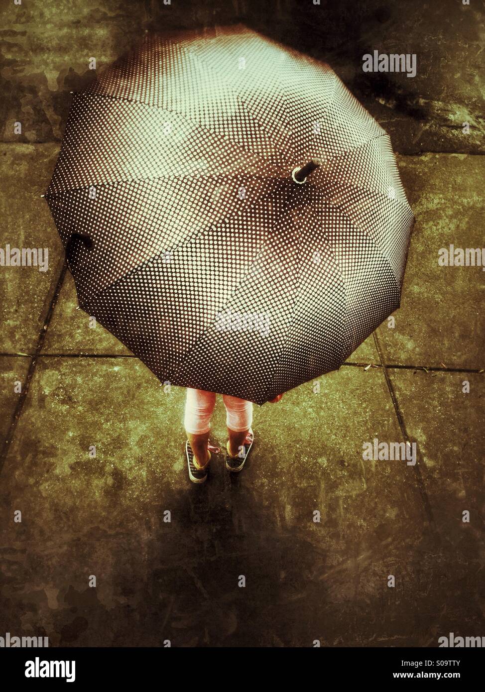 Little girl under an umbrella on a rainy day. Stock Photo