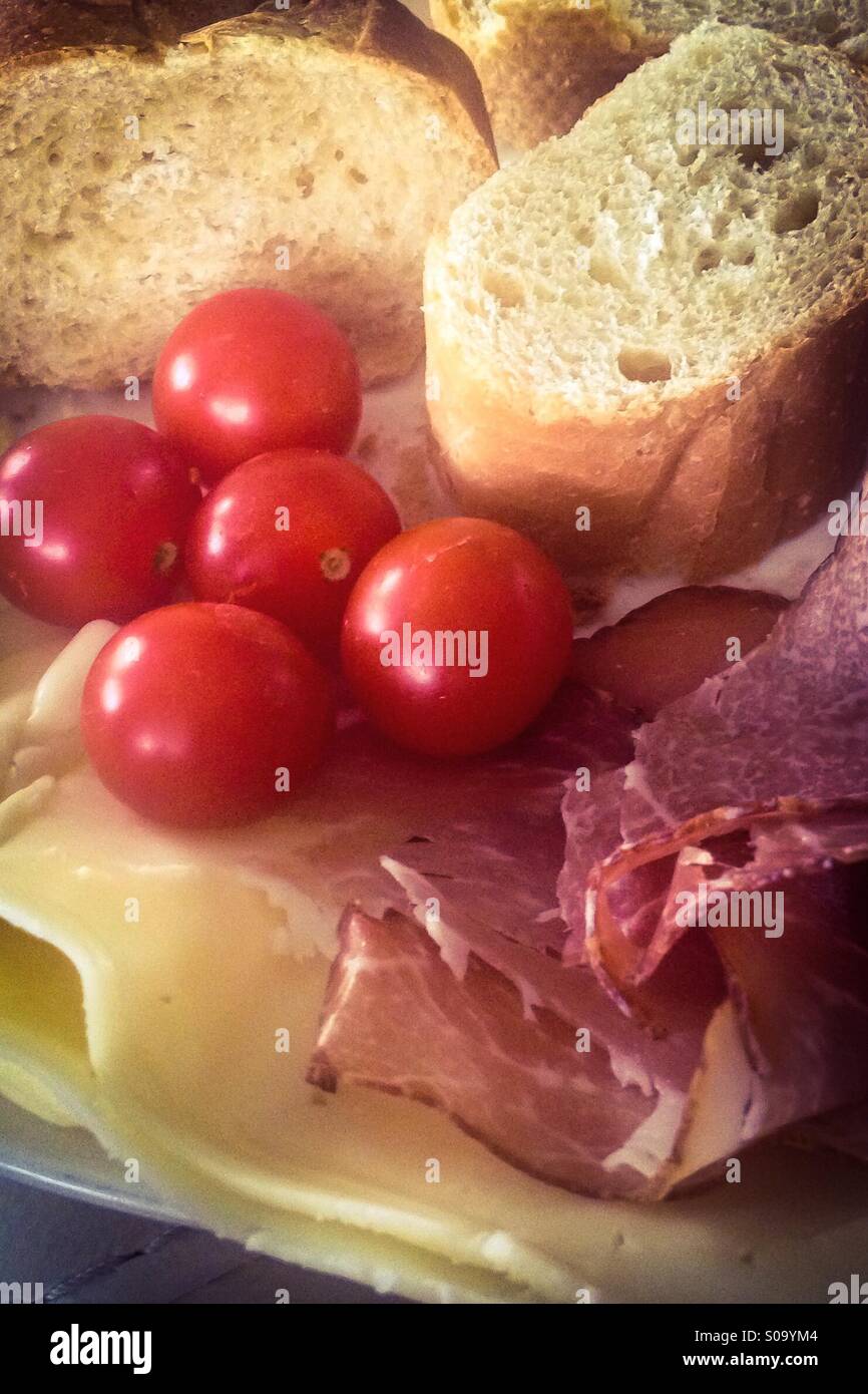 A light meal of fresh bread, cured meats, cheese and cherry tomatoes