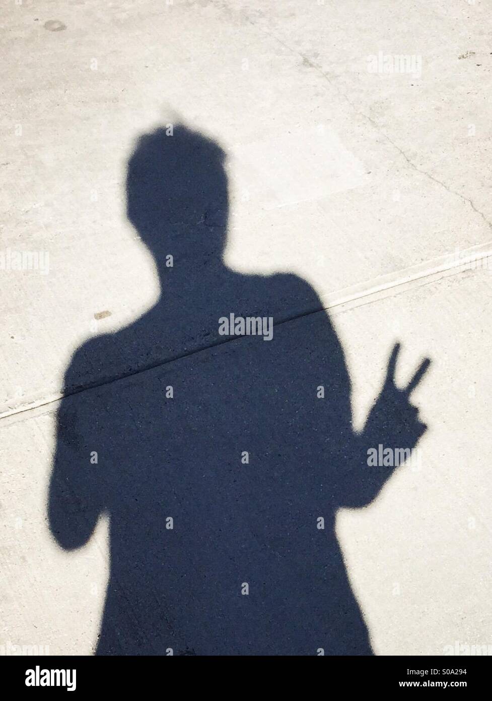 Shadow of a male giving the peace sign. Stock Photo