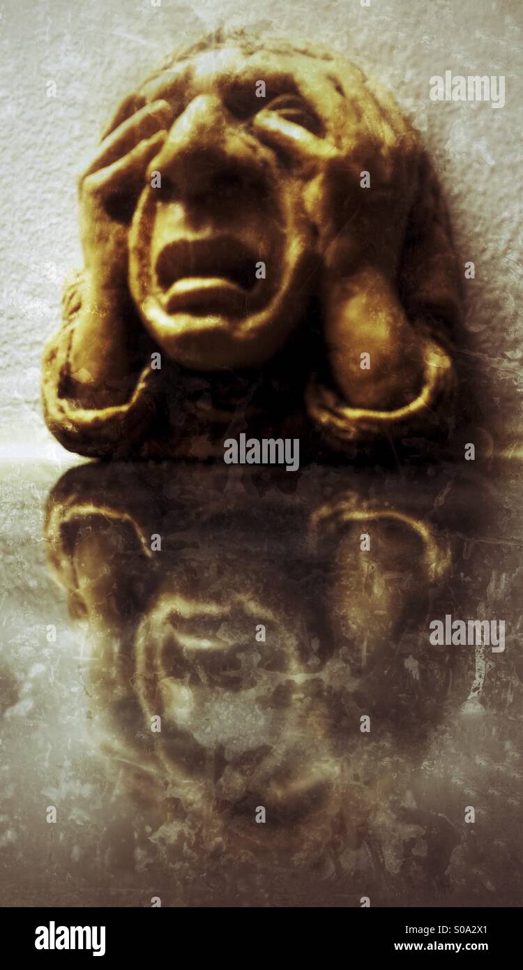 Stone carved head called 'Misery' gargoyle (AKA grotesque) wall plaque