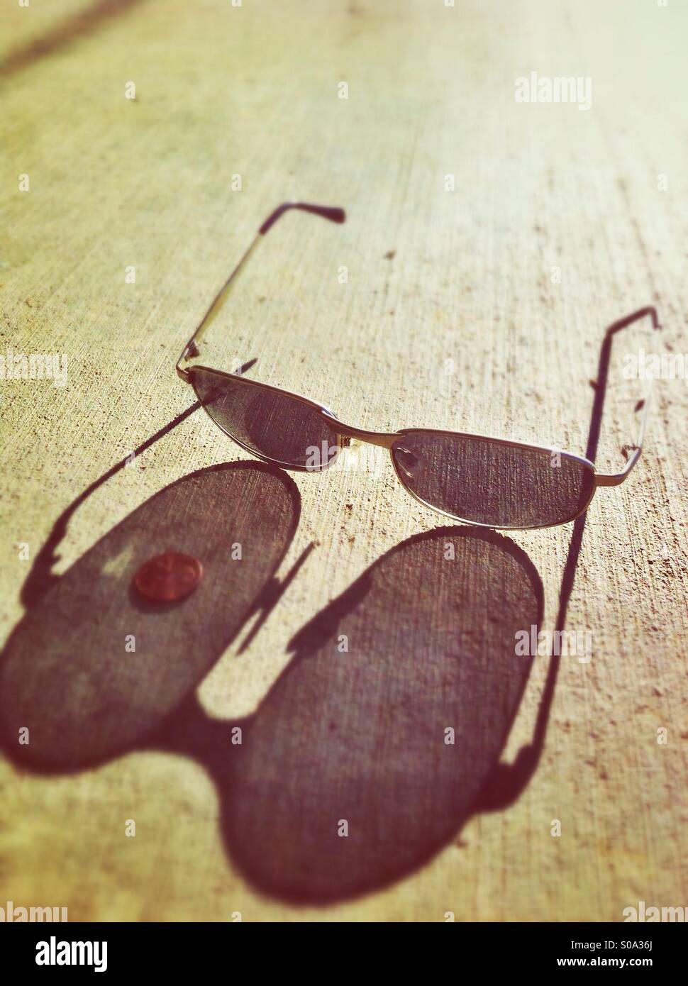 Sunglasses on the pavement casting long shadows - Smartphone Captured Stock Image